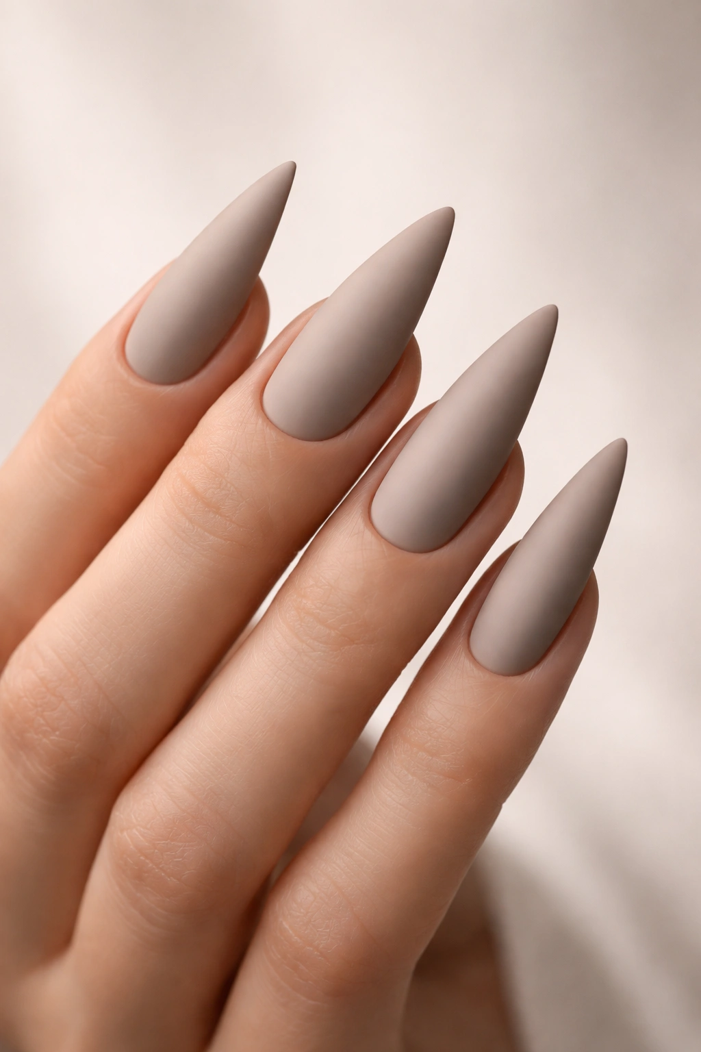 Close-up of greige velvet-matte stiletto nails on a hand