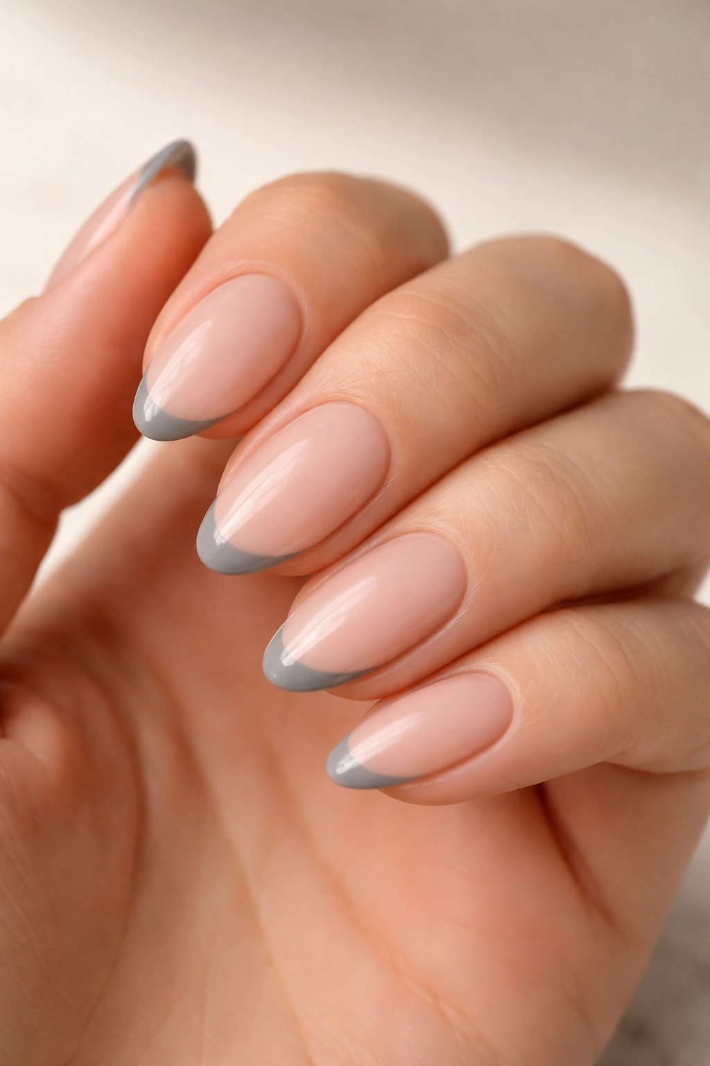 Short almond nails with grey French tips on nude base