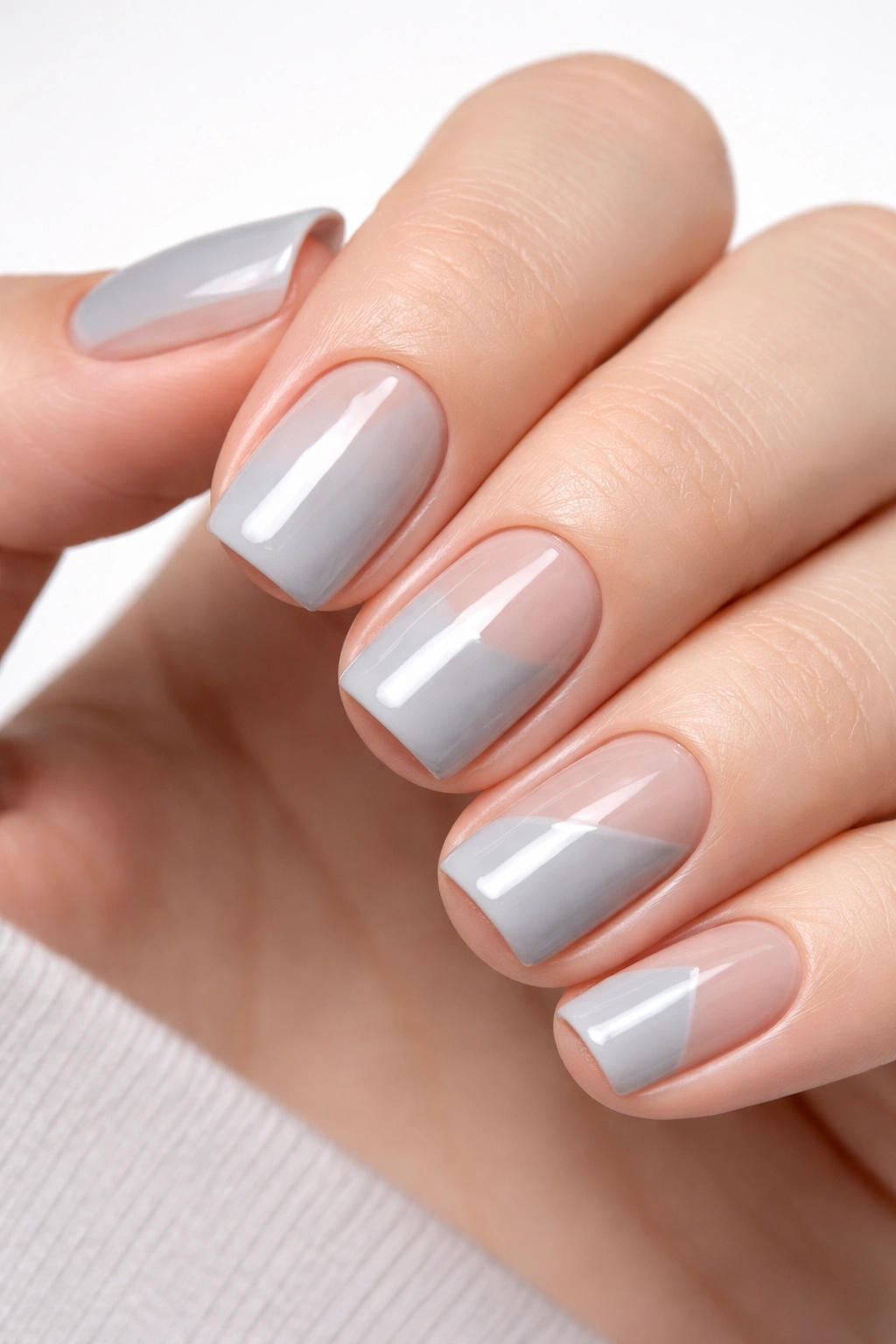 Close-up of soft grey nails featuring geometric negative space design
