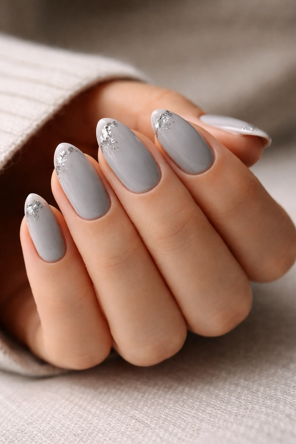 Short almond nails with grey polish and tiny silver foil accents