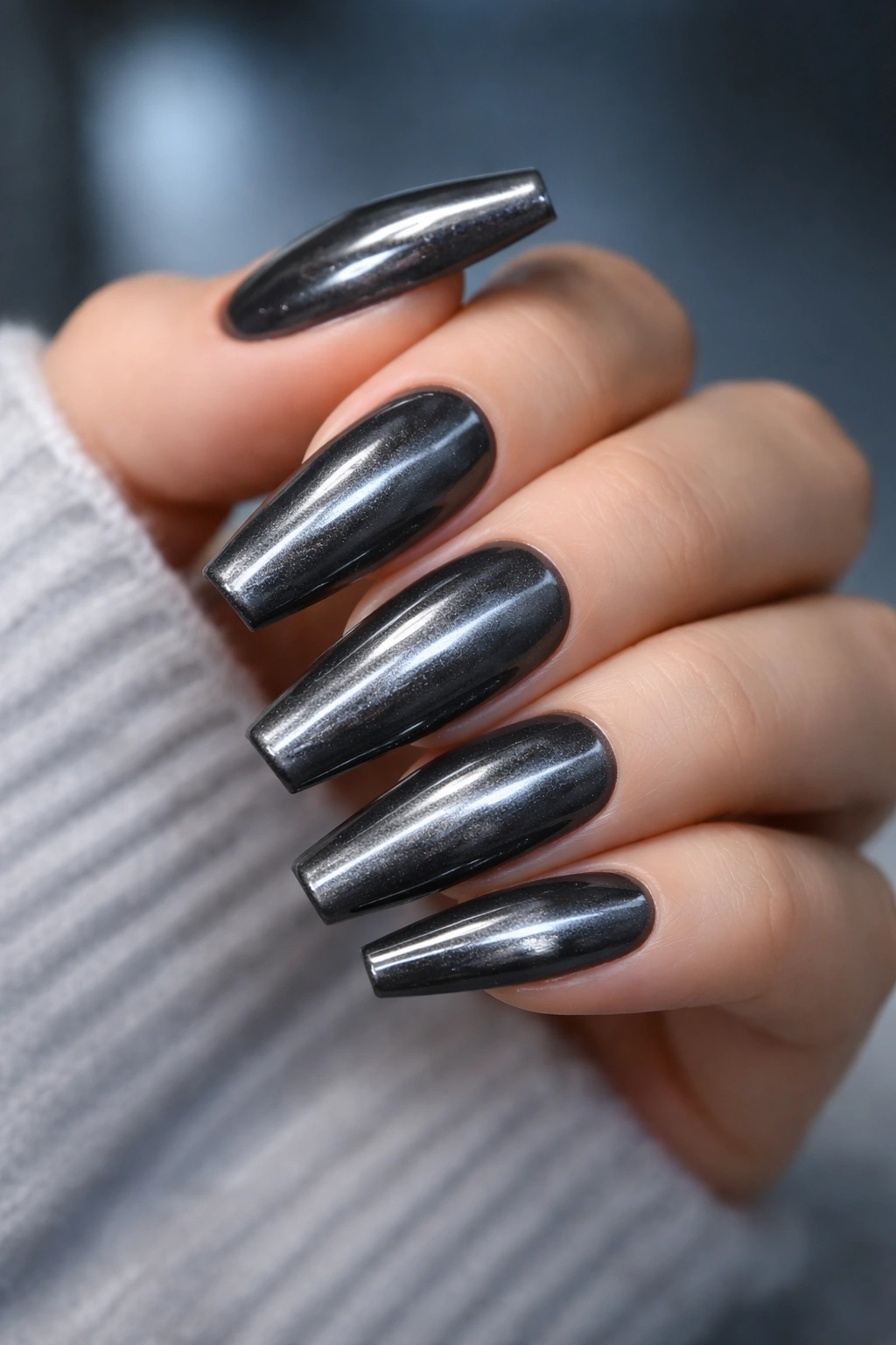 Close-up of gunmetal cat eye ballerina nails with steel flash on a hand