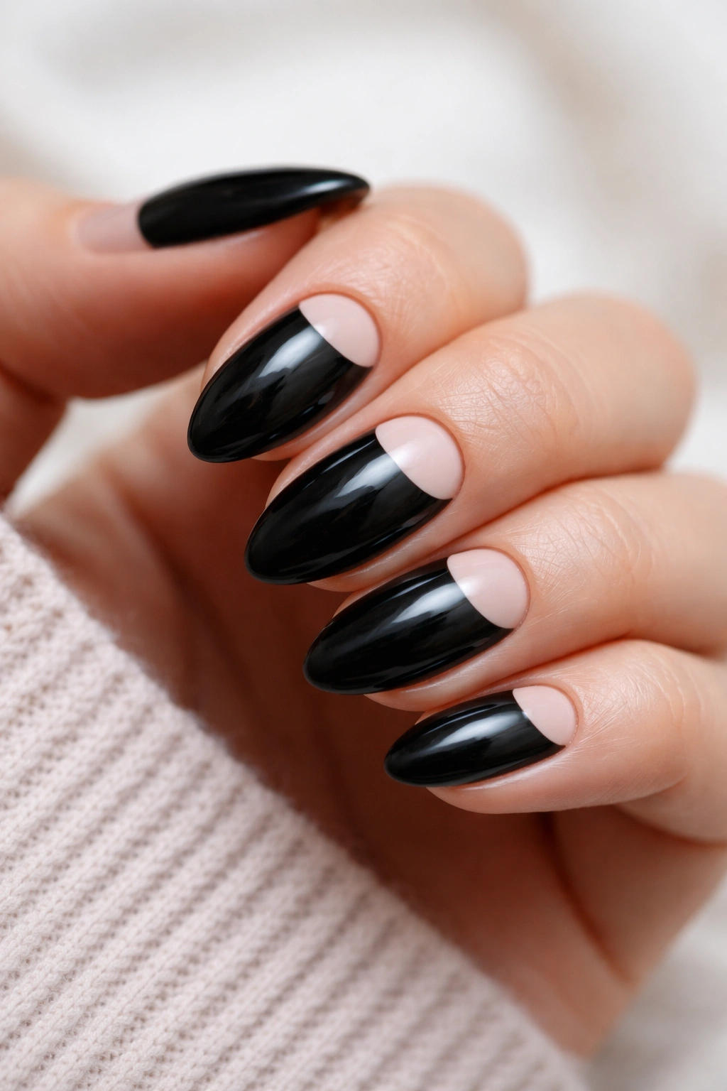 Close-up of half-moon black almond nails with pale crescent