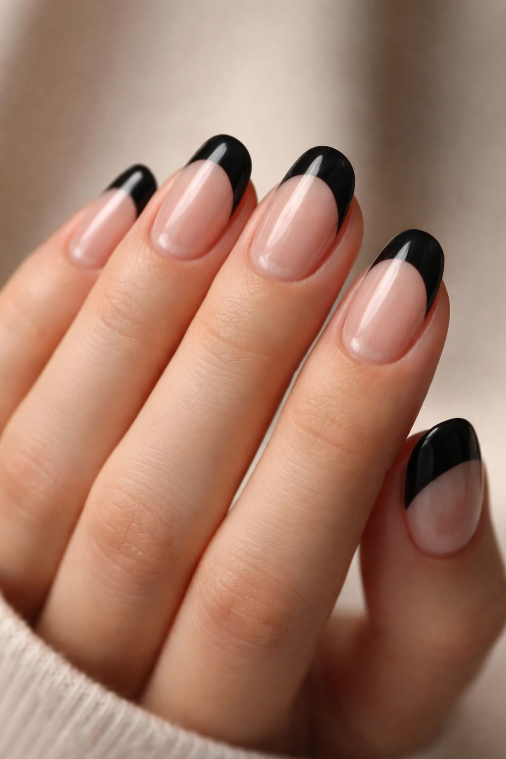 Close-up of short oval nails with a clear half-moon near the cuticle and black tips.