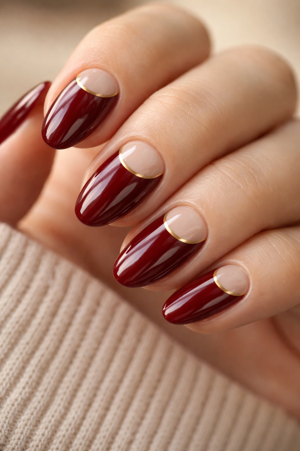 Close-up of short almond nails with nude half-moon base and wine red tips