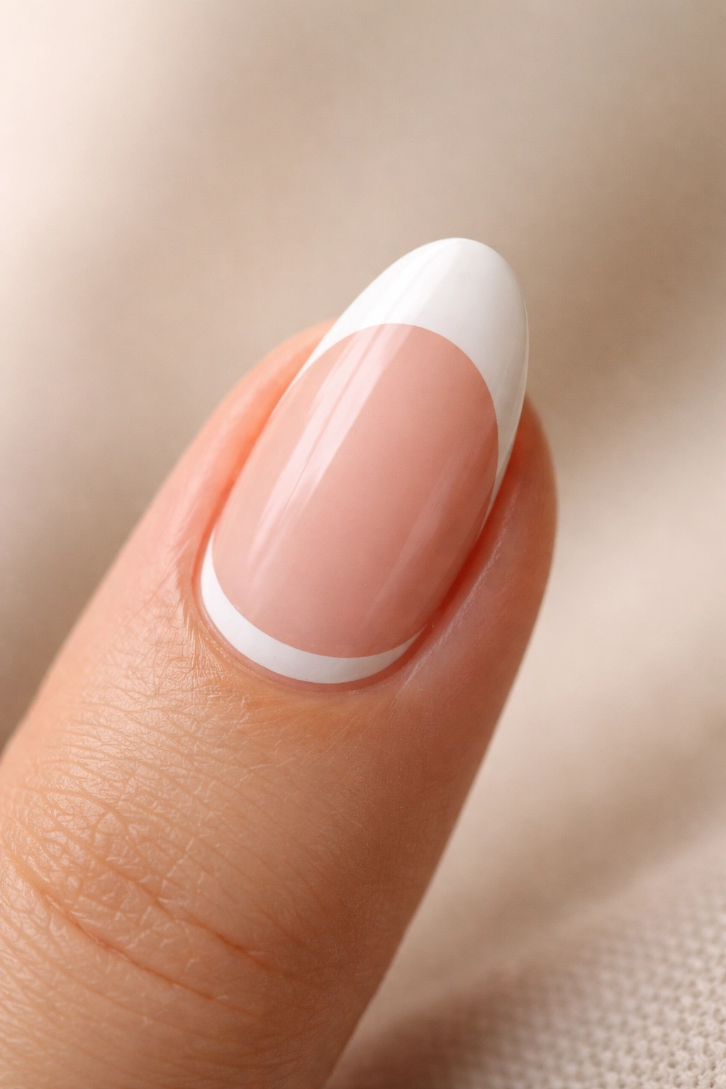 Close-up of a short almond nail with a white tip and subtle white half-moon at the cuticle.