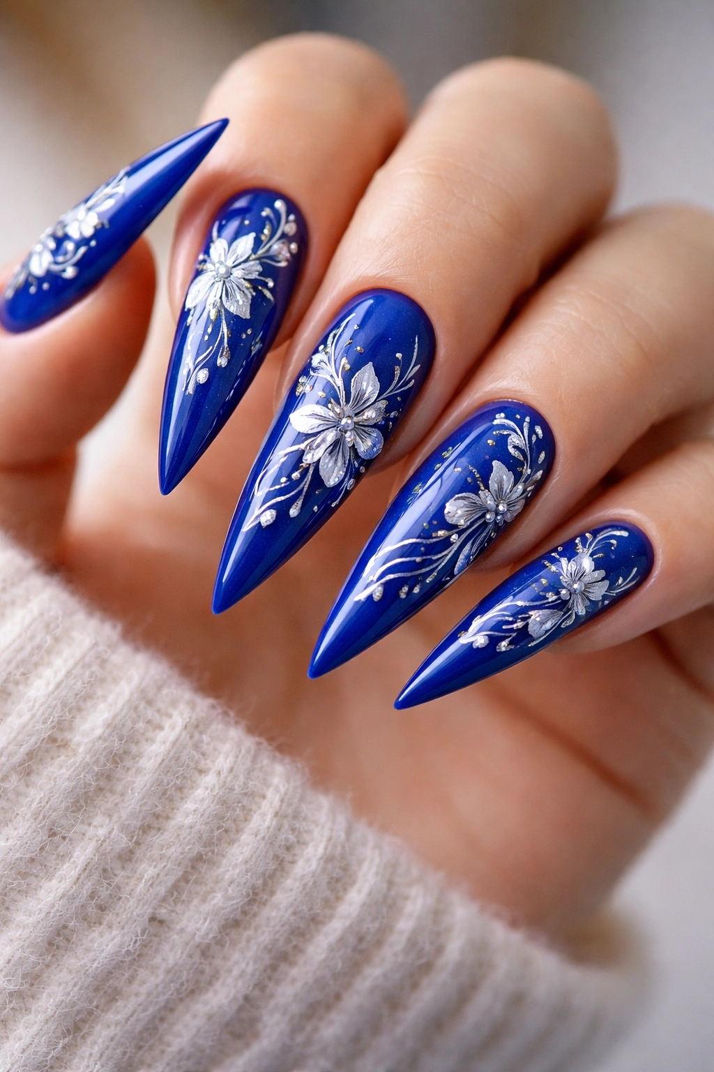 Close-up of royal blue nails with hand-painted floral details