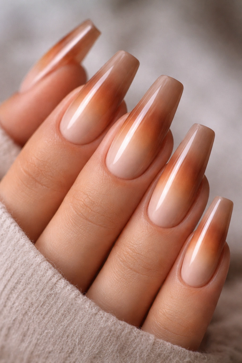 Close-up of hazelnut beige nails with a cinnamon aura centered on each nail