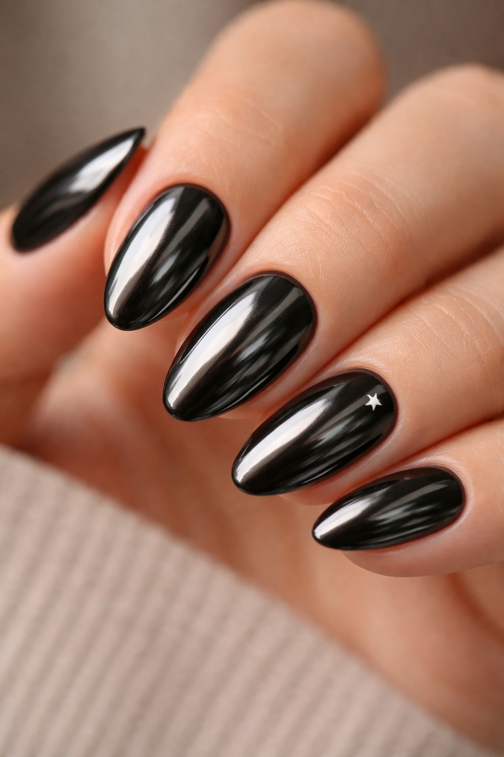 Close-up of black chrome nails with tiny heart/star accent on one nail