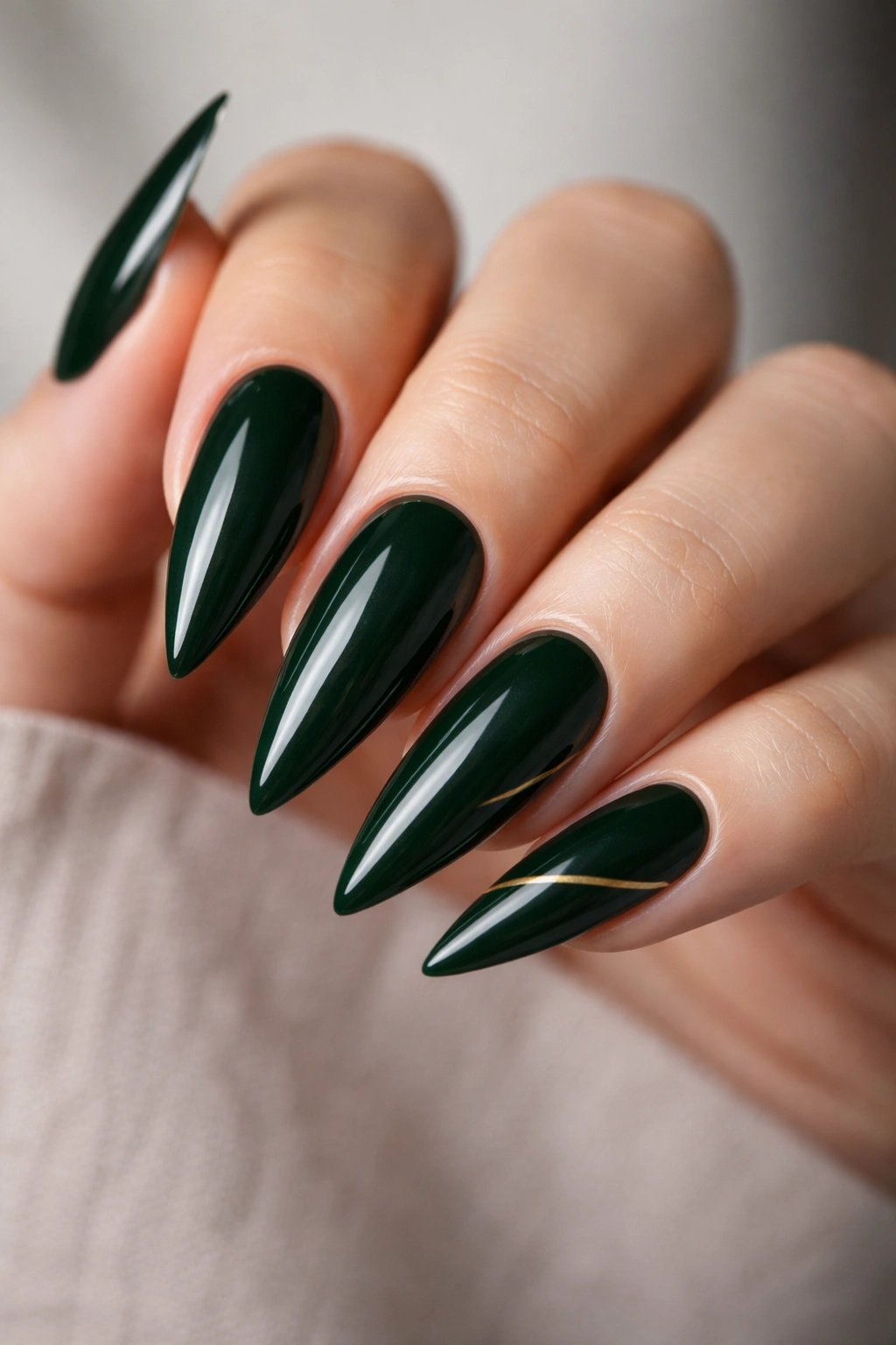 High-shine dark green stiletto nails with a minimalist gold accent nail