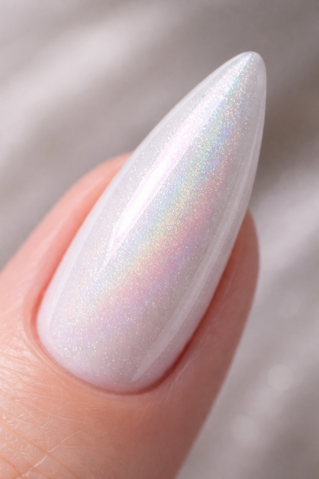 Close-up of white stiletto nail with holographic rainbow shimmer