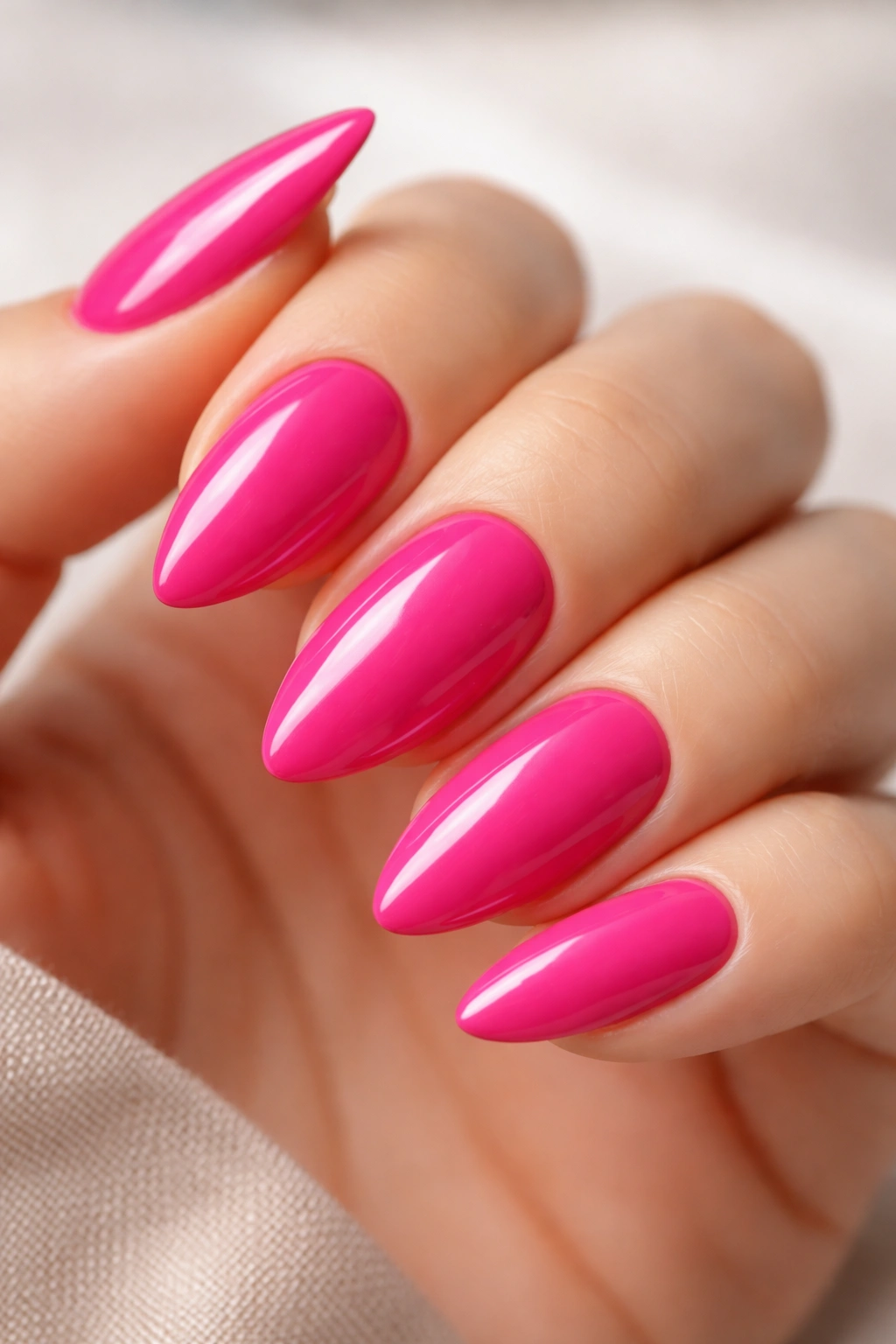 Close-up of hot pink almond nails with a glossy, vivid color.