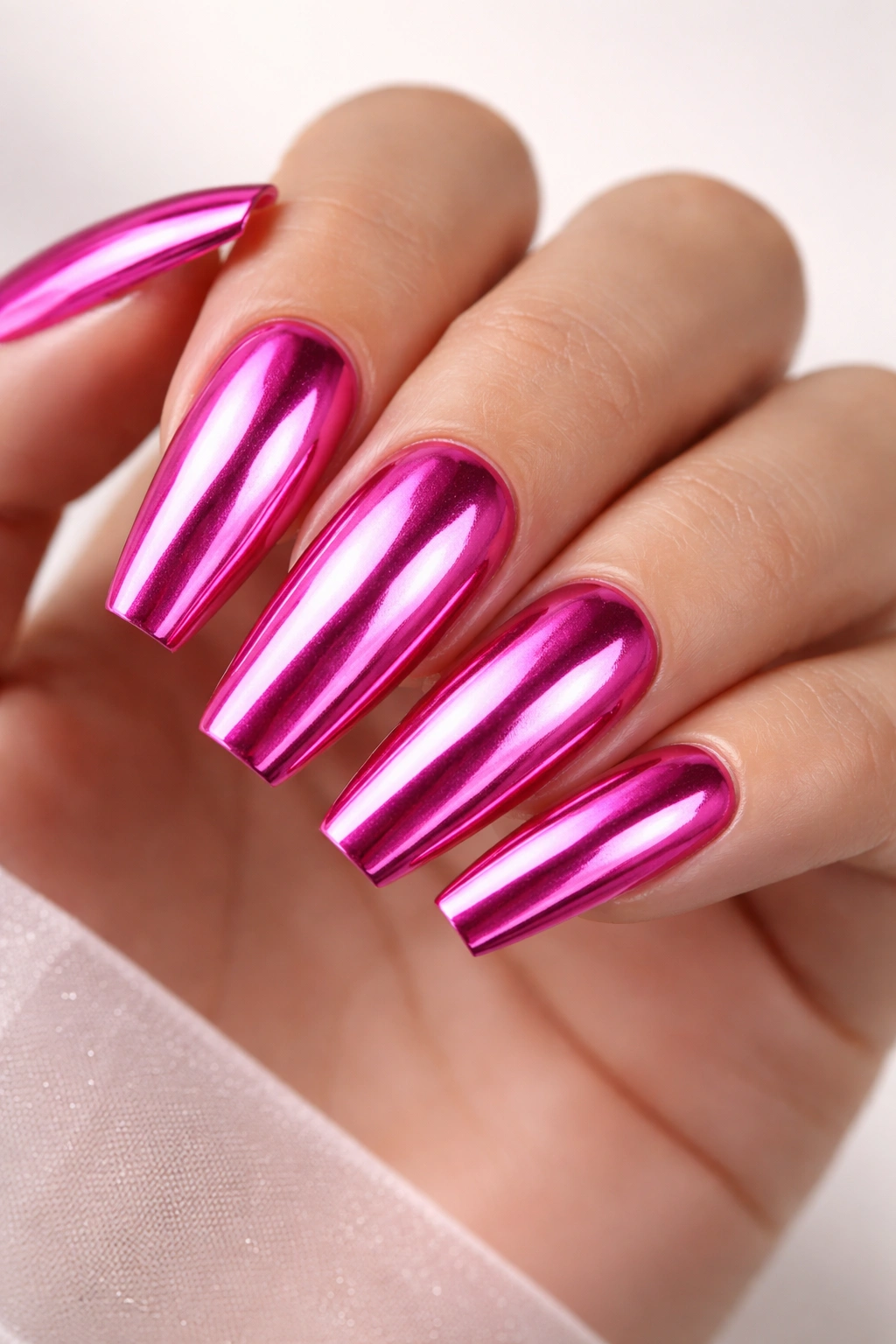 Close-up of hot pink chrome mirror nails on ballerina shape