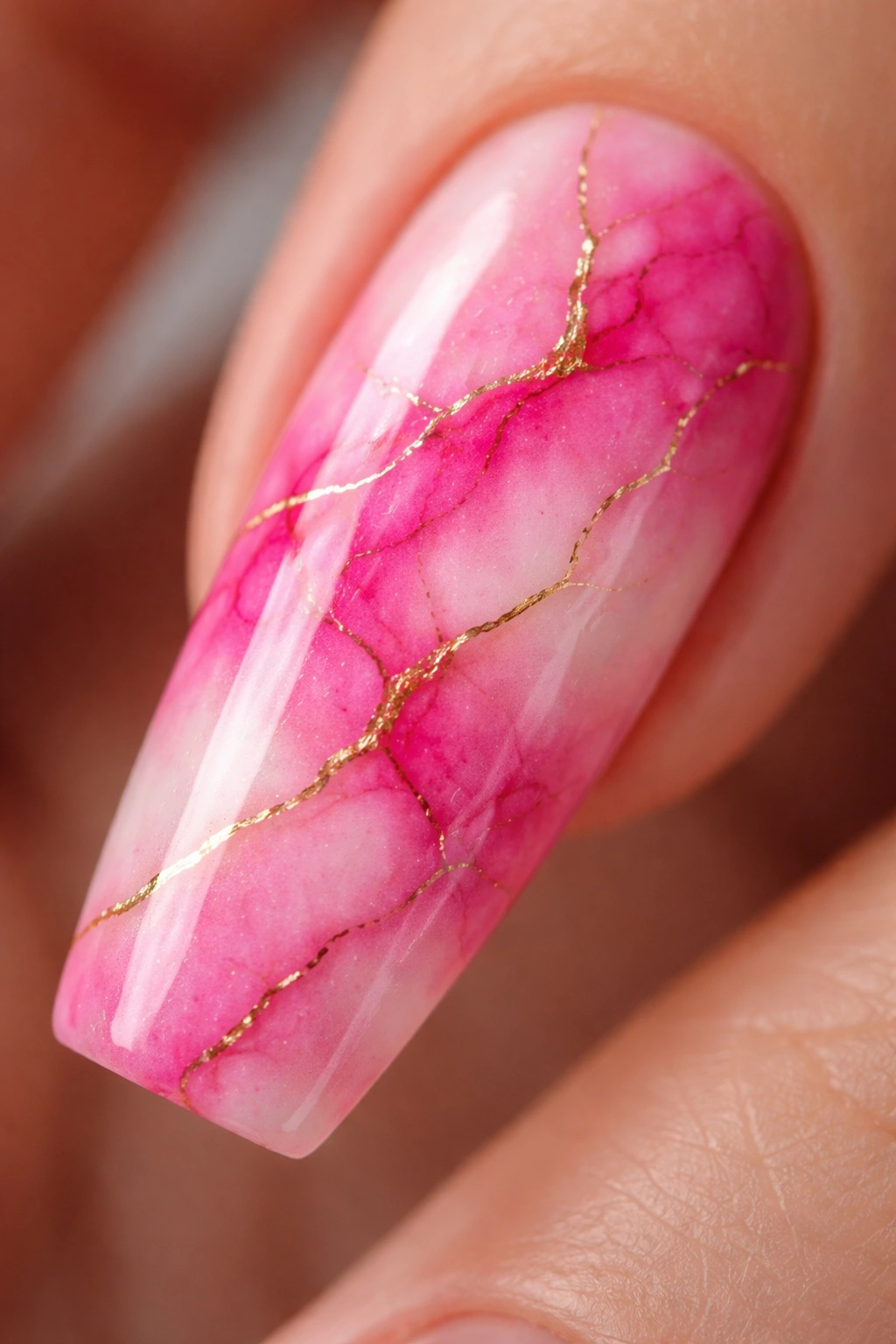 Close-up of a ballerina nail with hot pink marble and thin gold veins, glossy finish