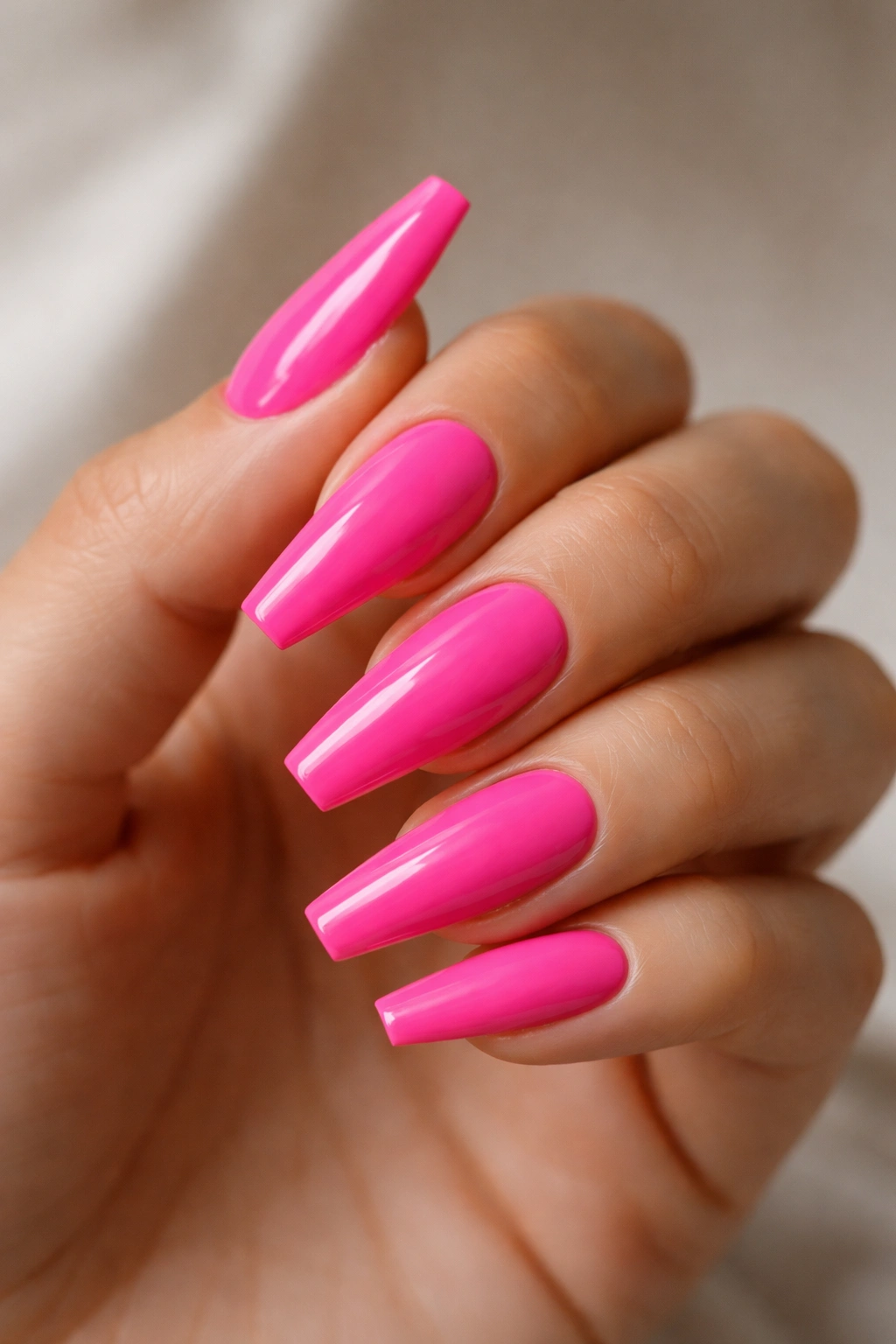 Close-up of hot pink ballerina nails with glossy finish and crisp tapered tips