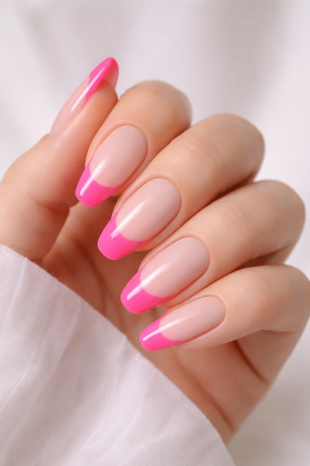 Close-up of nails with hot pink French tips on milky nude base