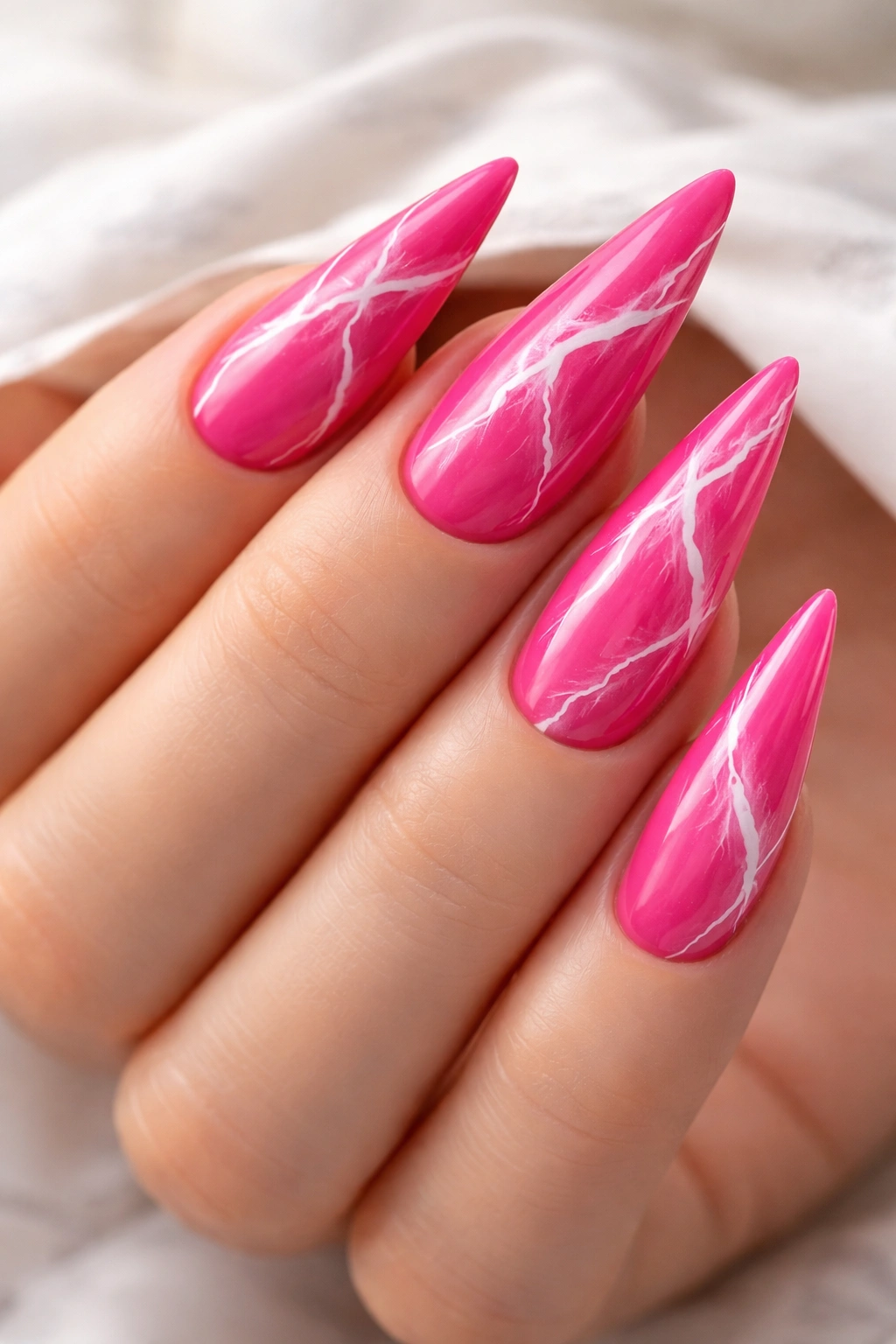 Close-up of hot pink stiletto nail with white marble veining