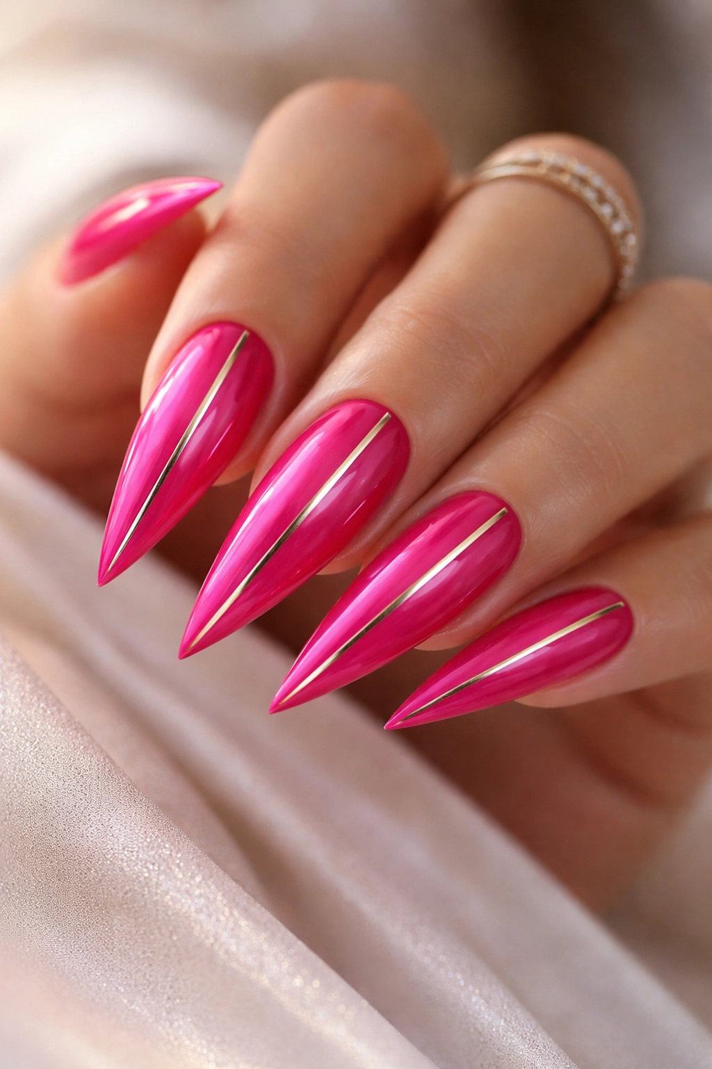 Hot pink stiletto nails with gold metallic accents and glossy finish