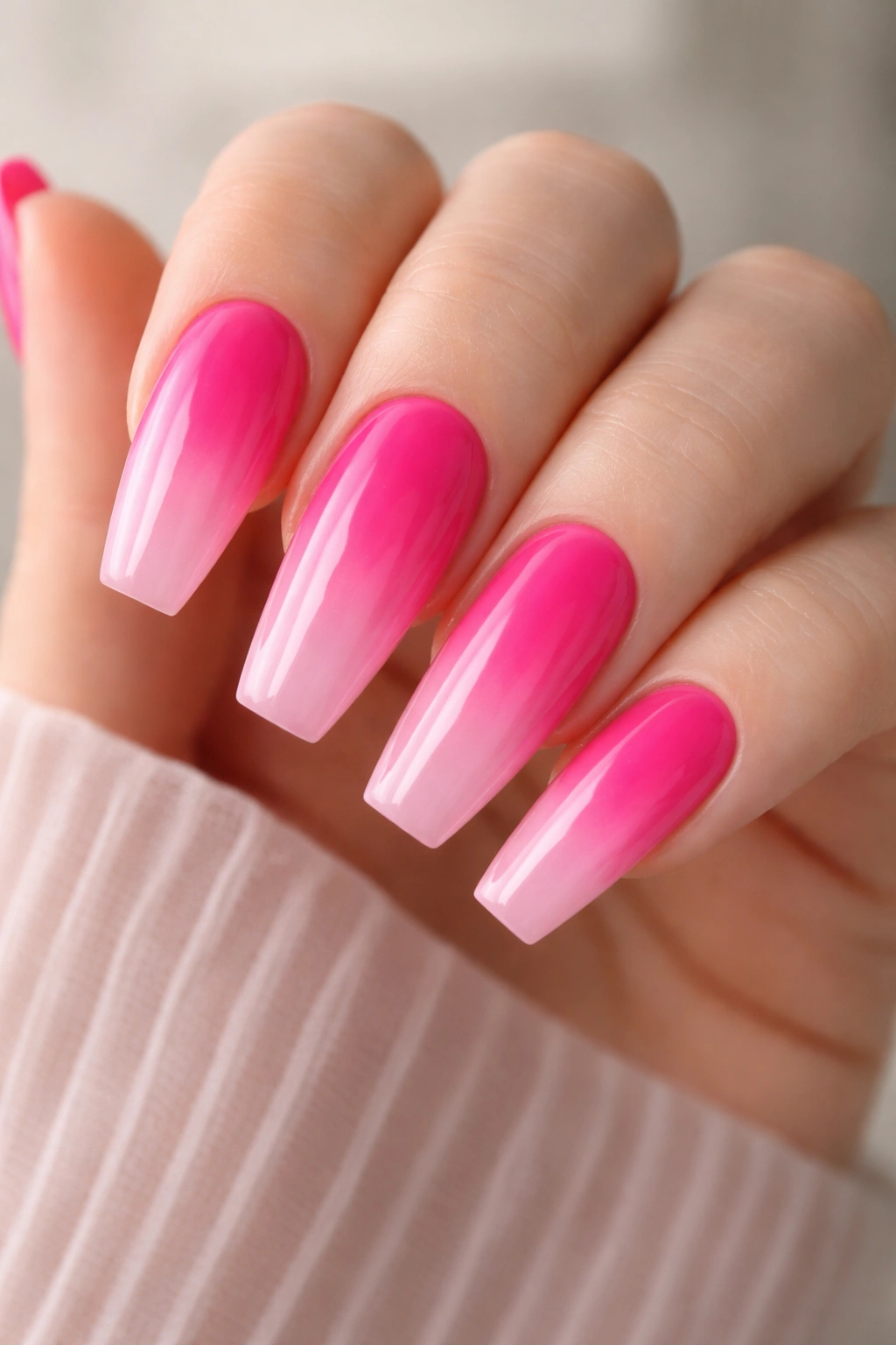 Close-up of ballerina nails with hot pink to baby pink ombre and glossy top coat