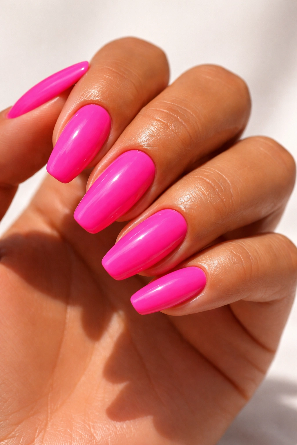Close-up of hot pink nails on tan skin
