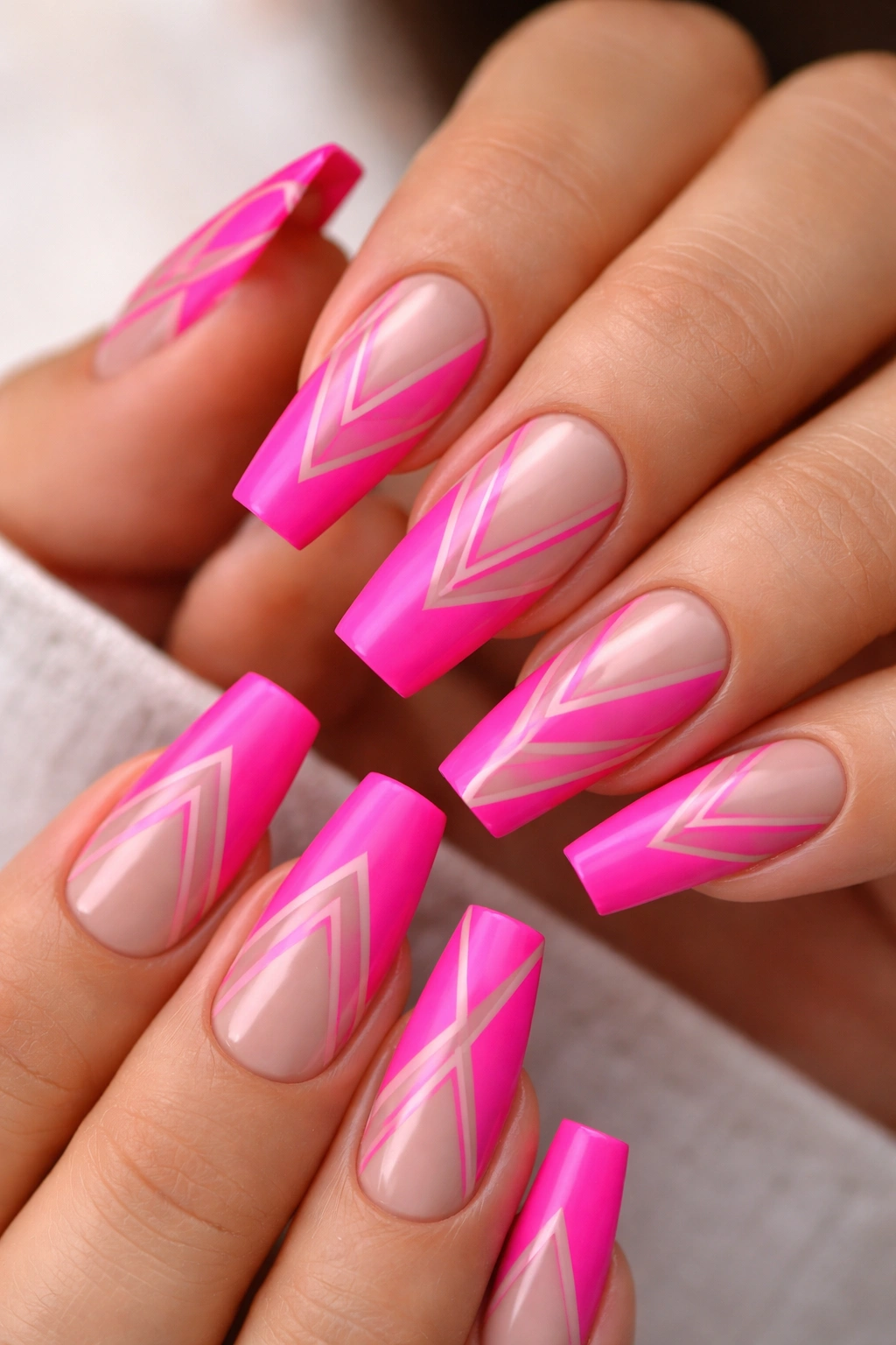 Close-up of hot pink coffin nails with negative-space geometric patterns on medium-length nails