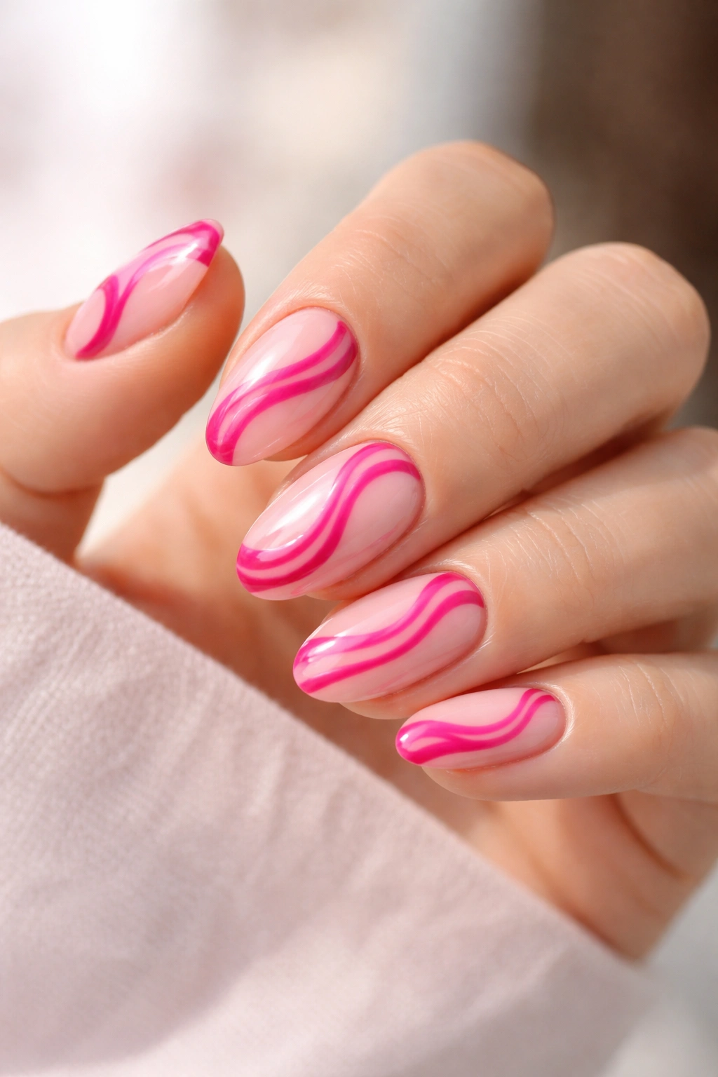 Close-up of short almond nails with hot pink swirls on sheer pink base