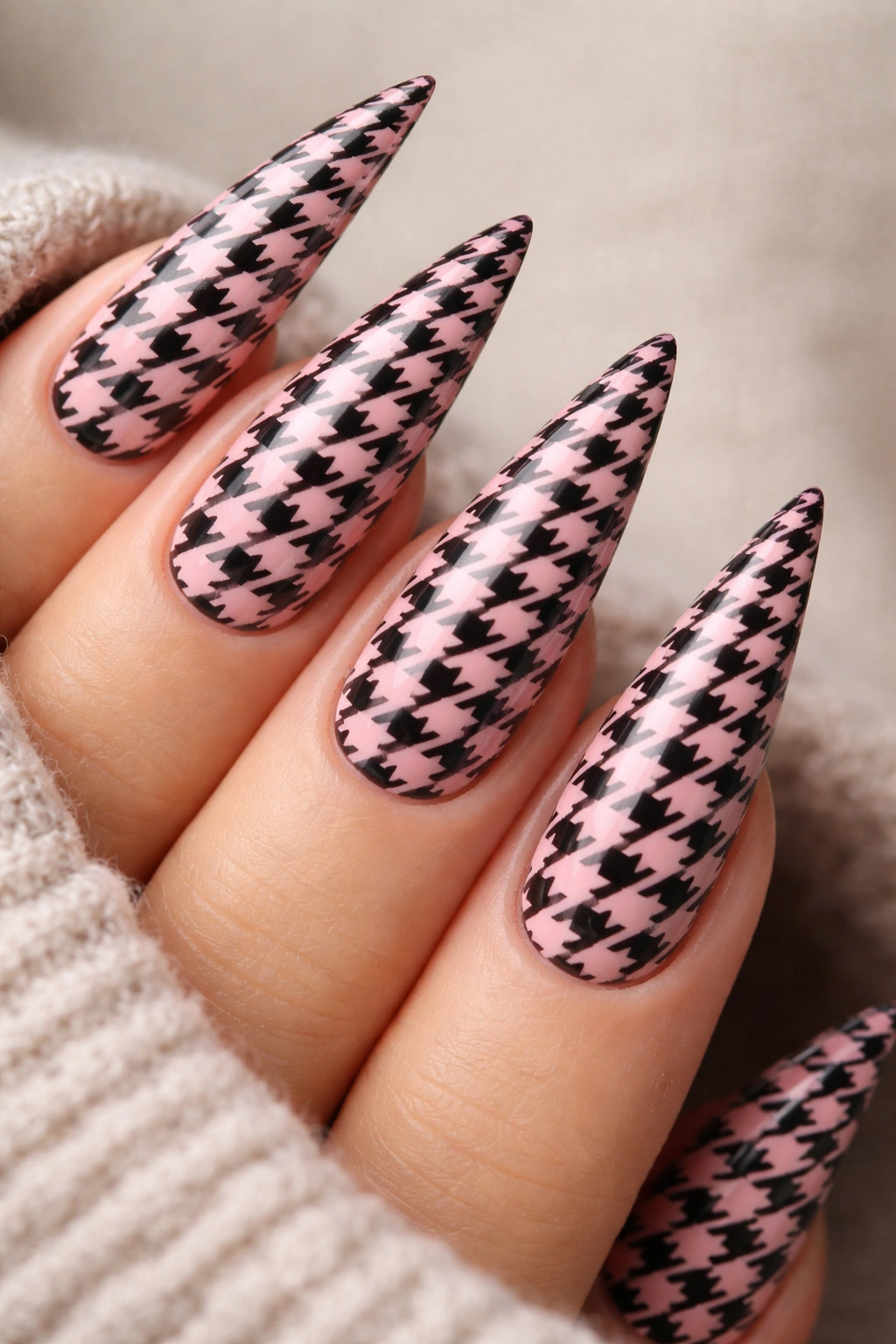 Close-up of pink stiletto nails with small black and pink houndstooth pattern