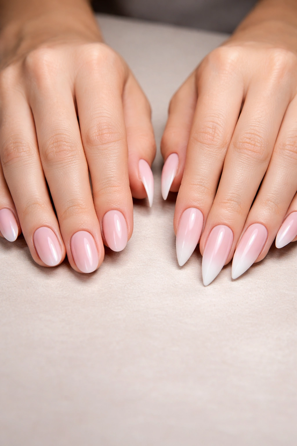 Close-up of hands with round and stiletto nails on a neutral surface, illustrating hybrid nail styles