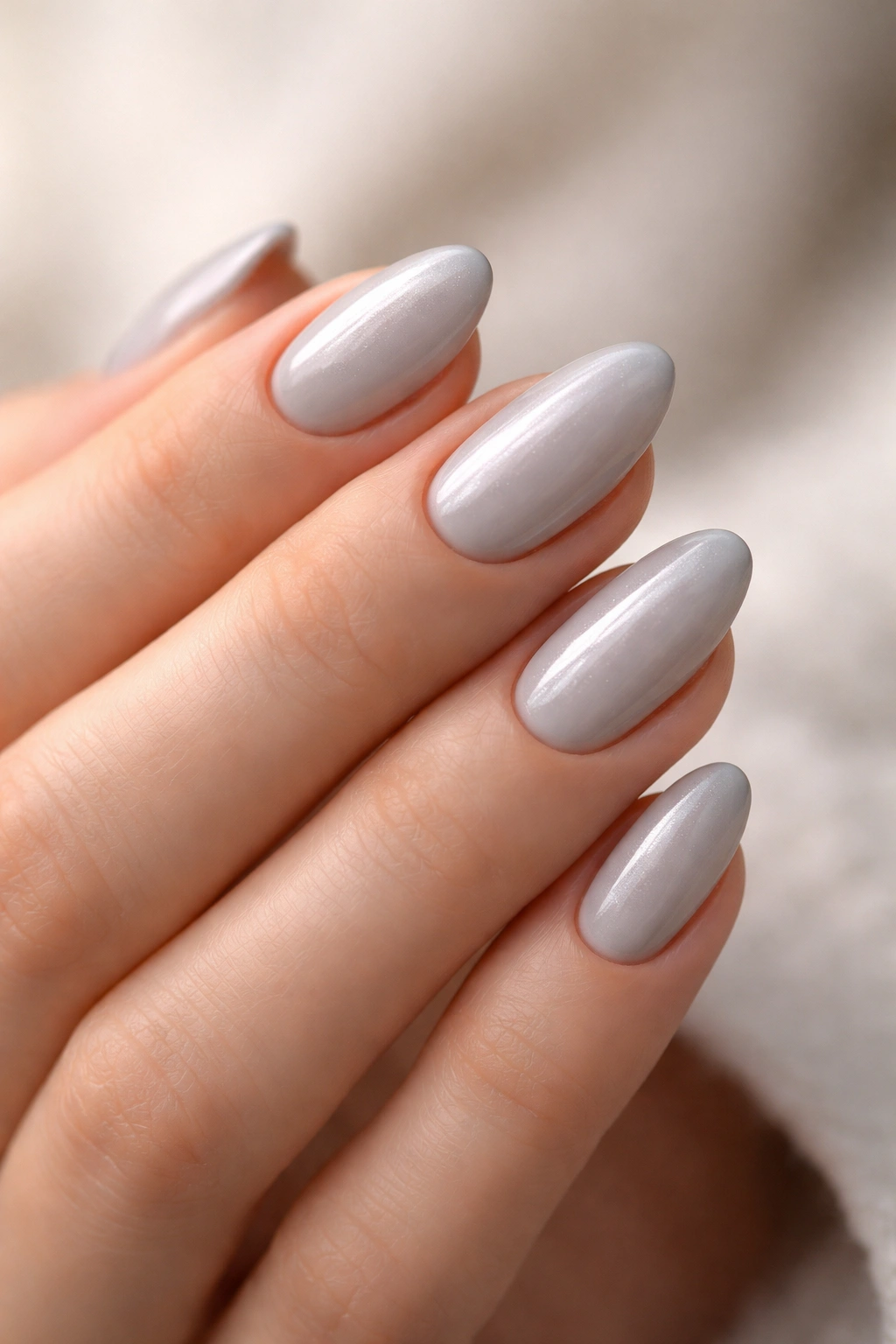Close-up of soft ice-gray almond nails with a subtle silvery sheen on a clean hand.