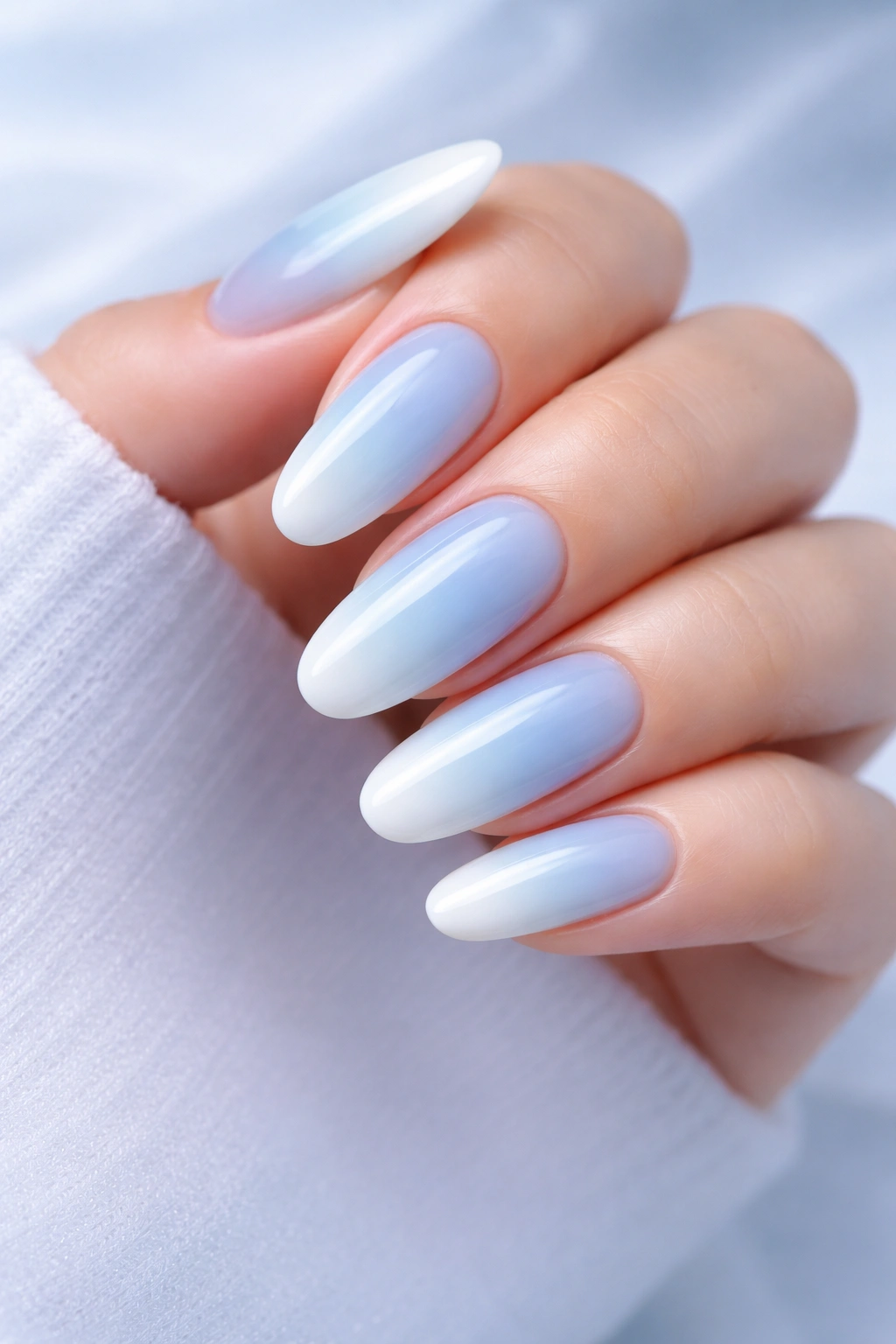 Close-up of long rounded nails with icy blue gradient fading to white tips