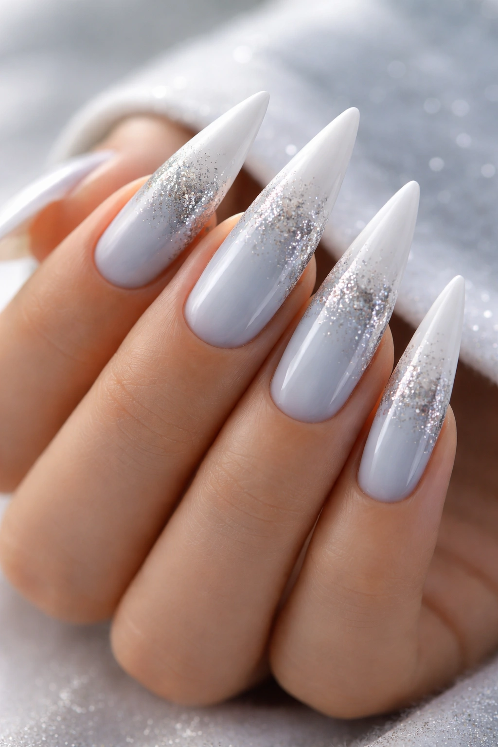 Icy pale blue nails with white tips and silver glitter gradient on stiletto shape