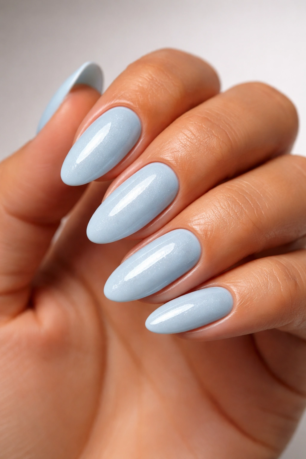 Icy blue nails on tan skin against a neutral backdrop
