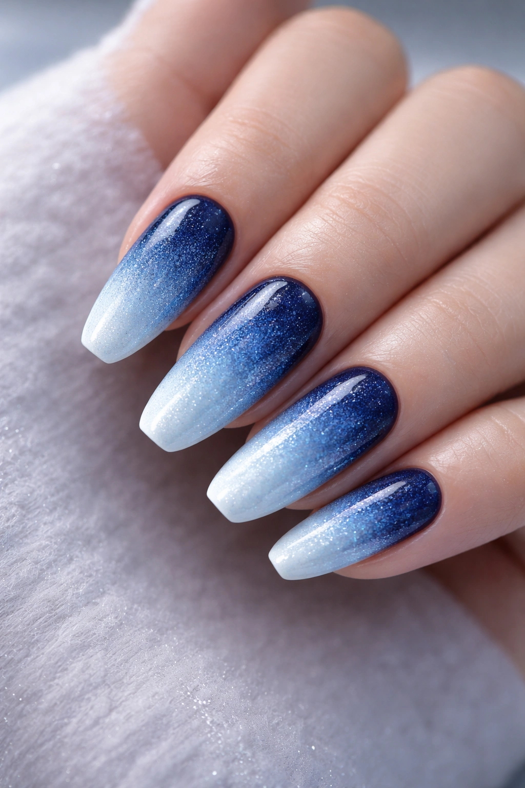 Close-up of icy blue ombre nails with navy-to-ice gradient and silver shimmer