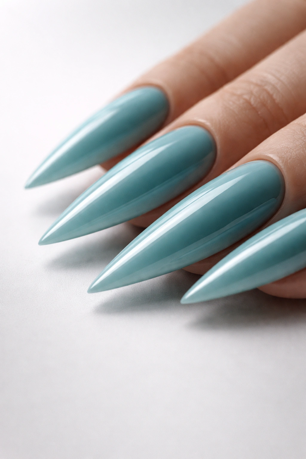 Icy teal glossy stiletto nails with subtle underside shadow