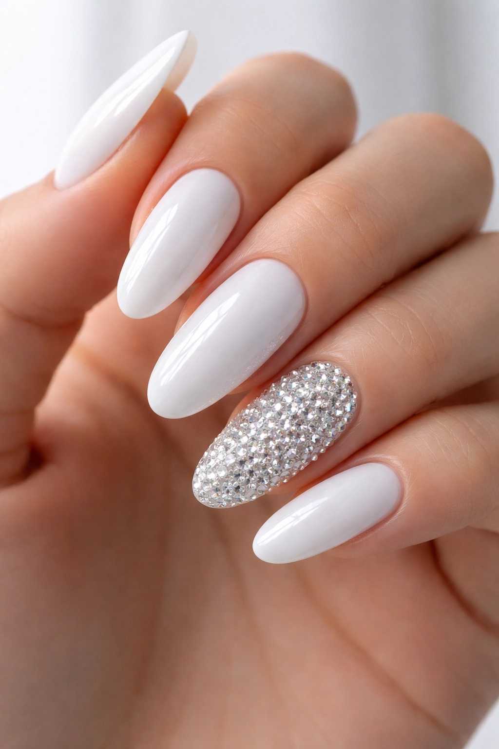 Icy white long oval nails with a fully encrusted accent nail on a hand