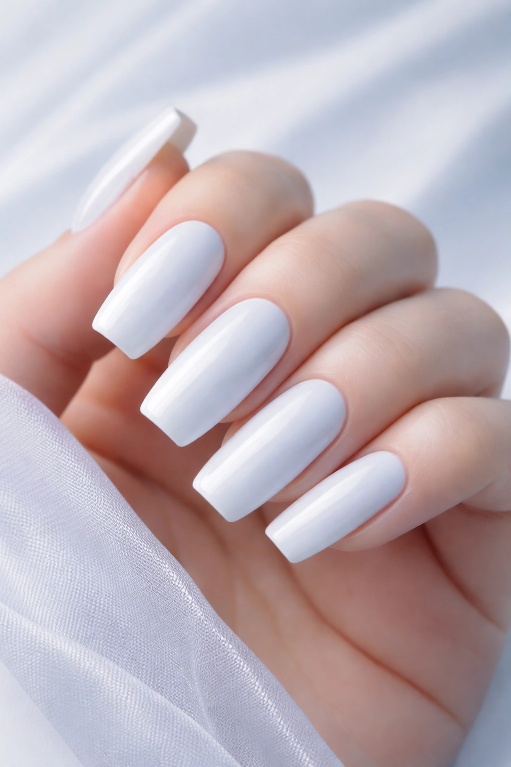 Close-up of long squoval nails in icy white with blue undertones