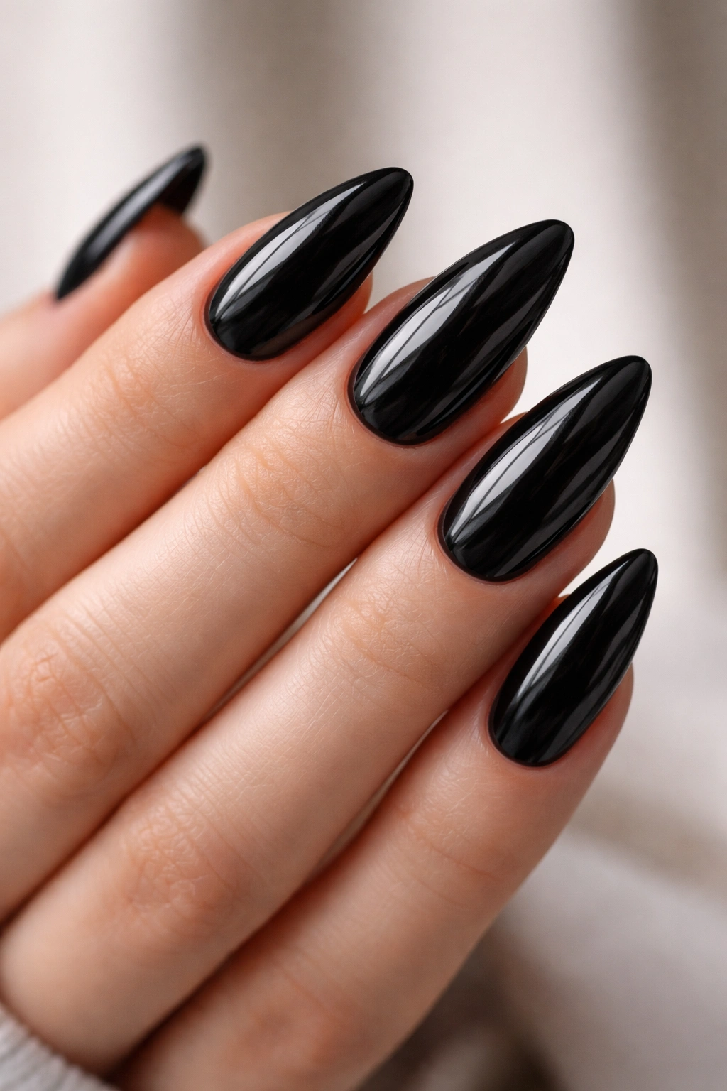 Close-up of almond-shaped nails in glossy ink-black color with deep, wet-look finish