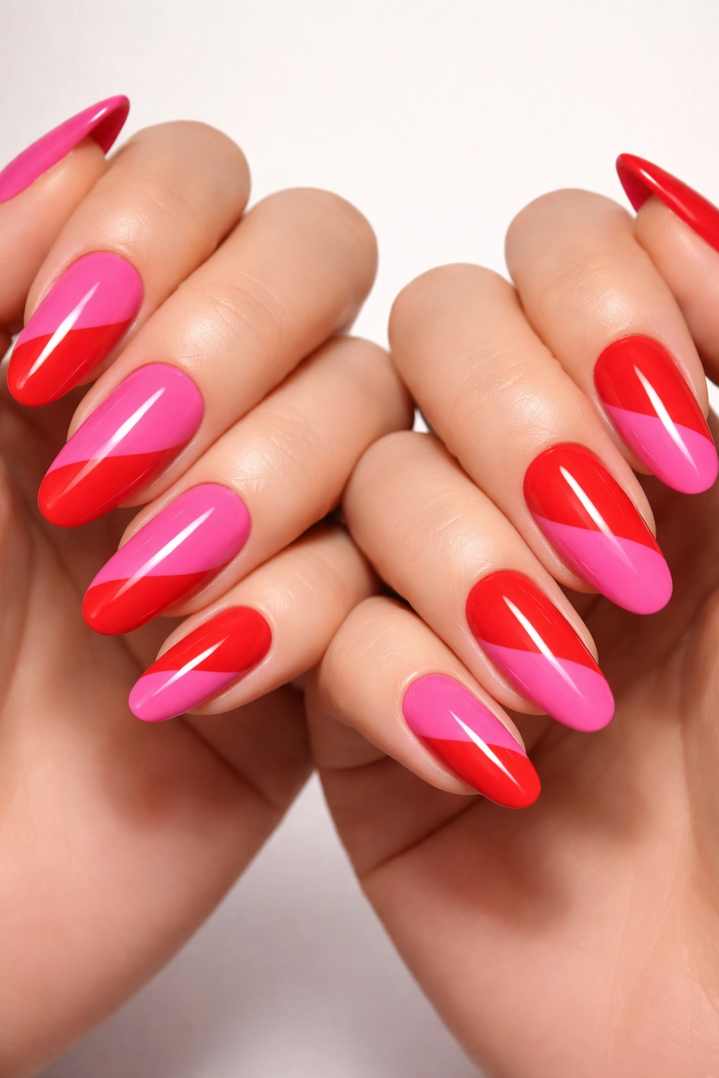Two hands with inverse color-blocked nails in pink and red