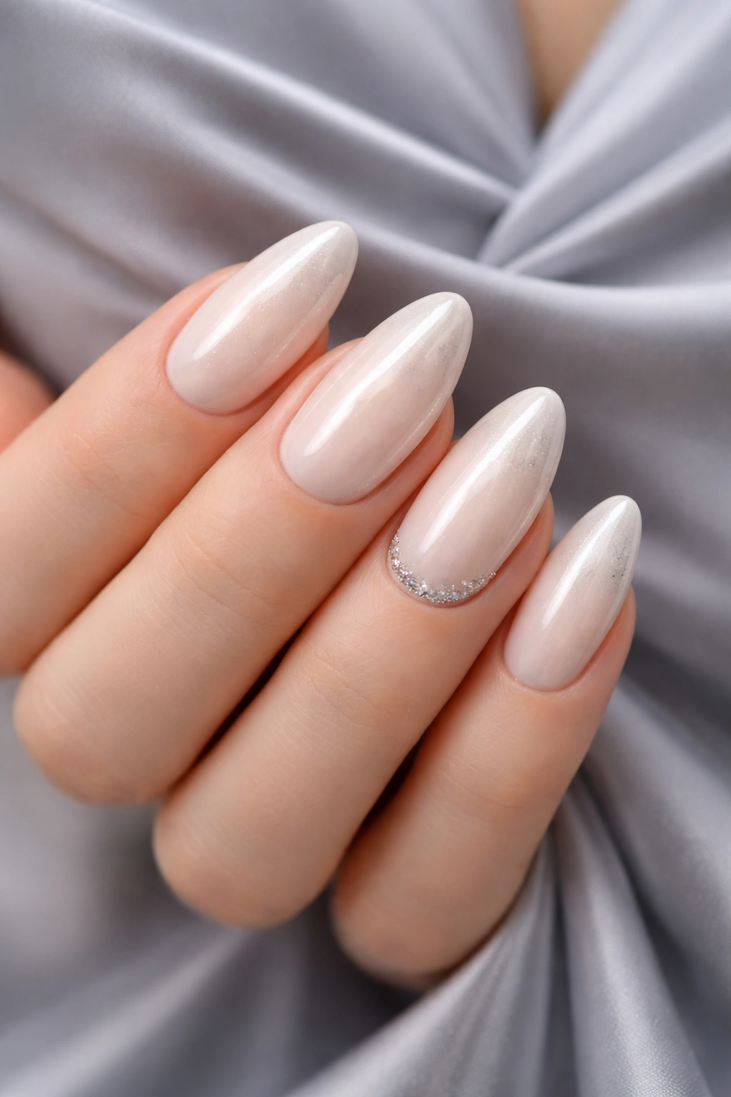 Creamy ivory nails with chrome shimmer against grey fabric