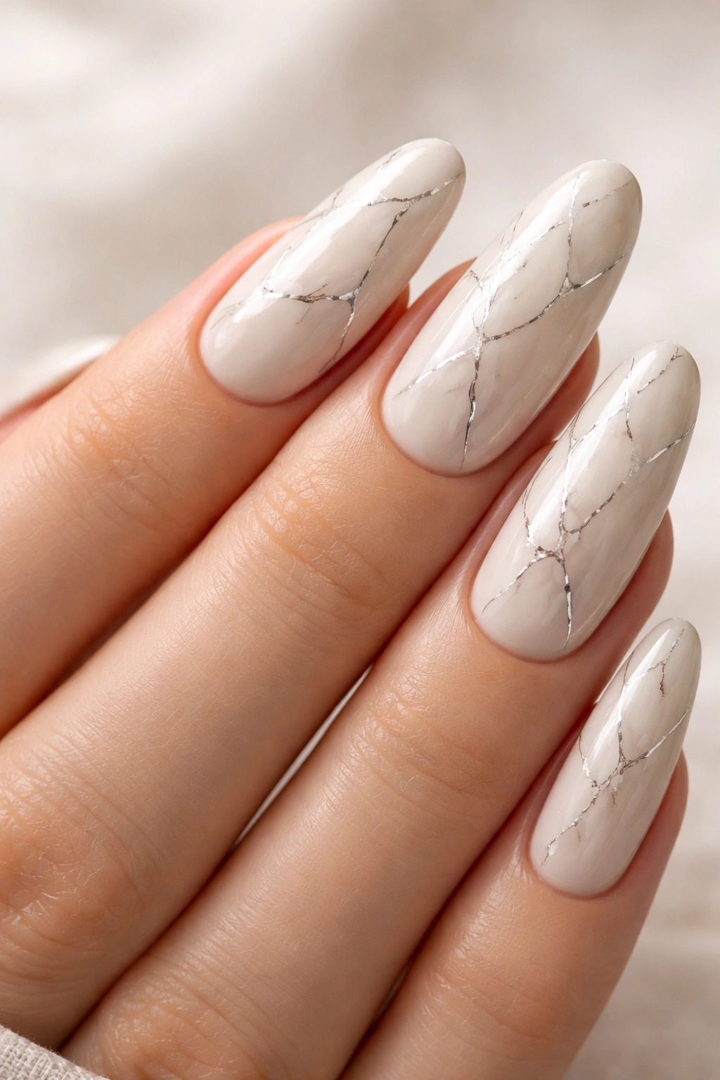 Close-up of ivory nails with silver veining on long oval nails