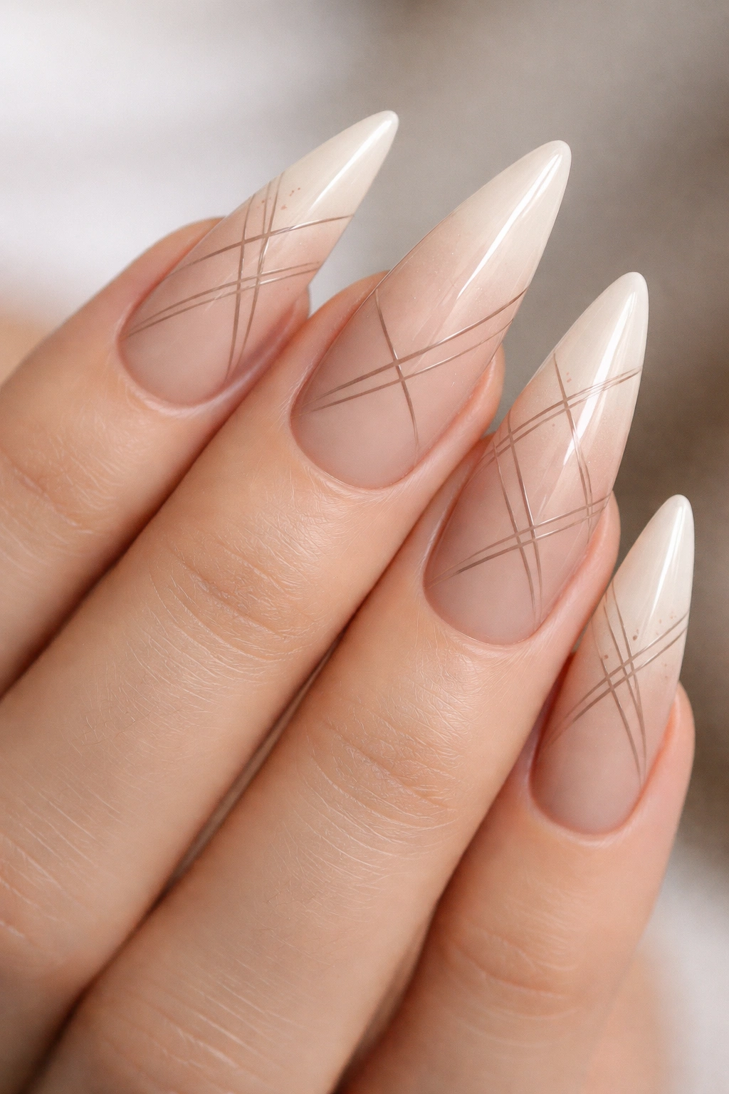 Ivory-to-nude stiletto nails with geometric lines.