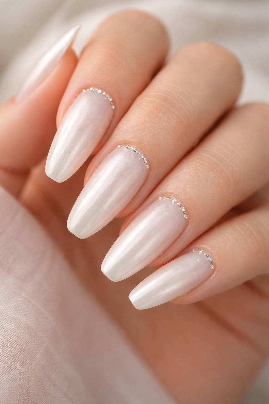 Ivory pearl ballerina nails with micro crystals at the cuticle on bare hand