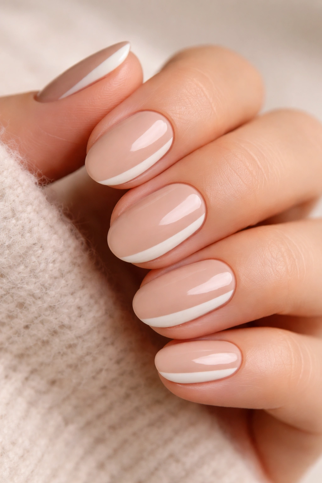 Close-up of short oval nails with ivory and sand color block design