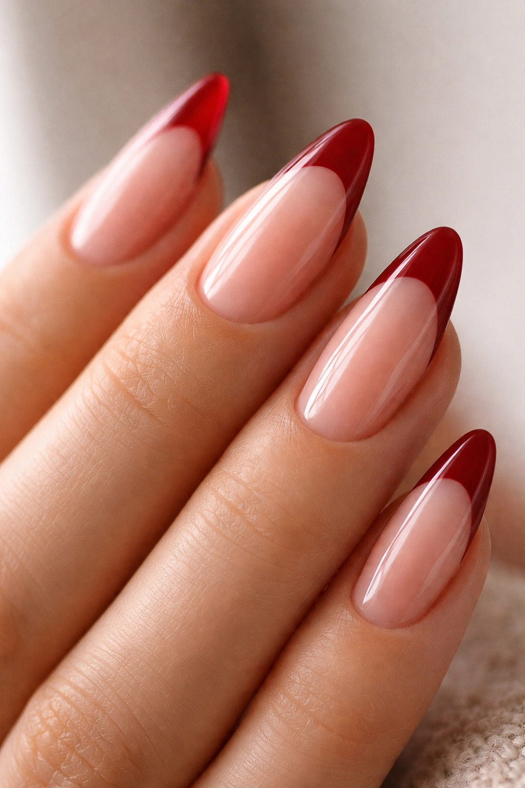 Almond nails with translucent jelly nude-pink base and deep red tips