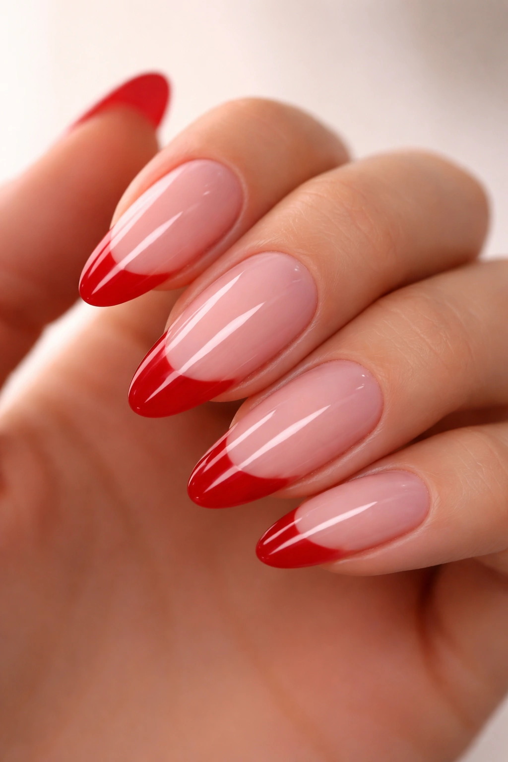 Almond nails with red tips on milky pink jelly base.