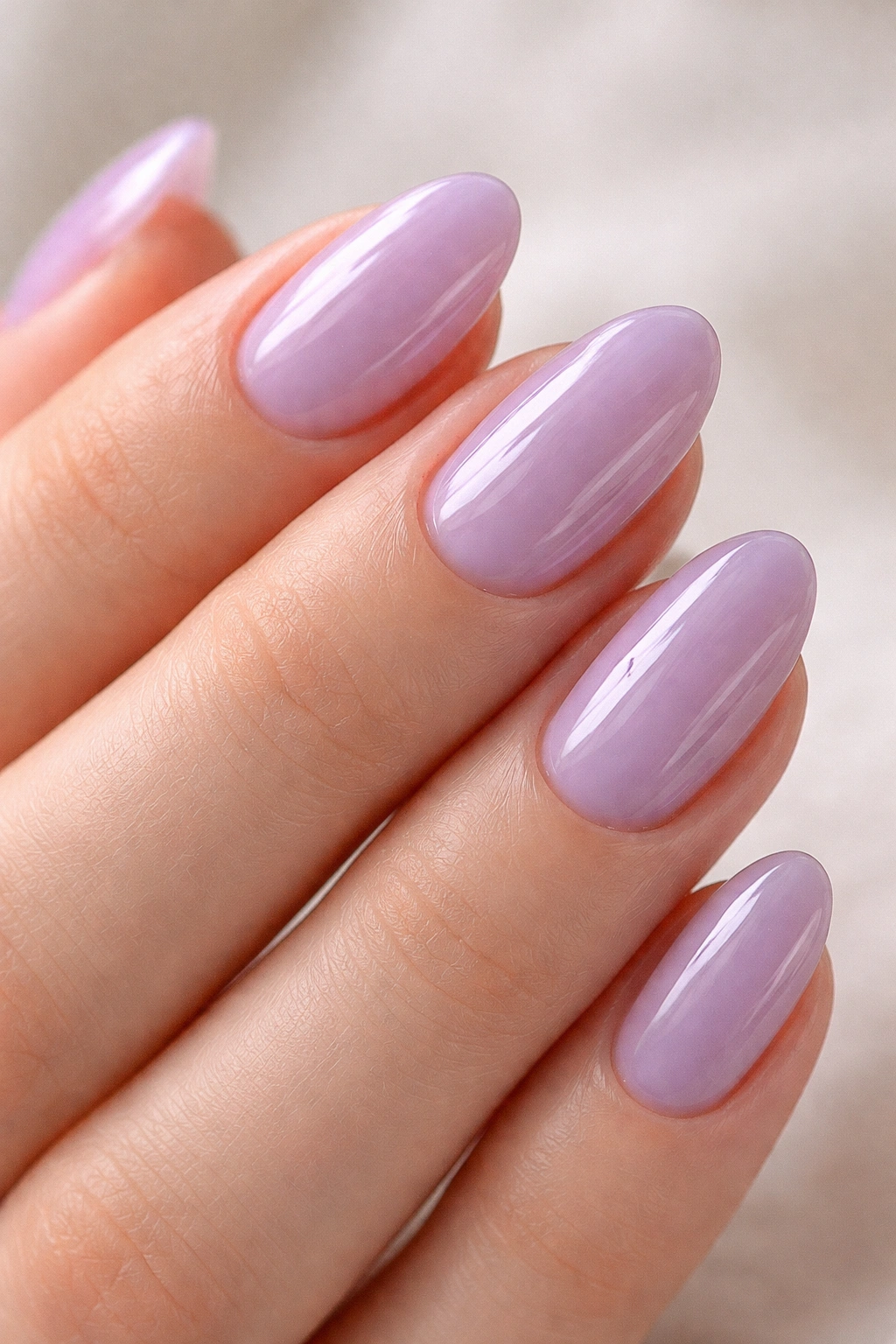 Close-up of short almond nails with a glossy lavender jelly finish.