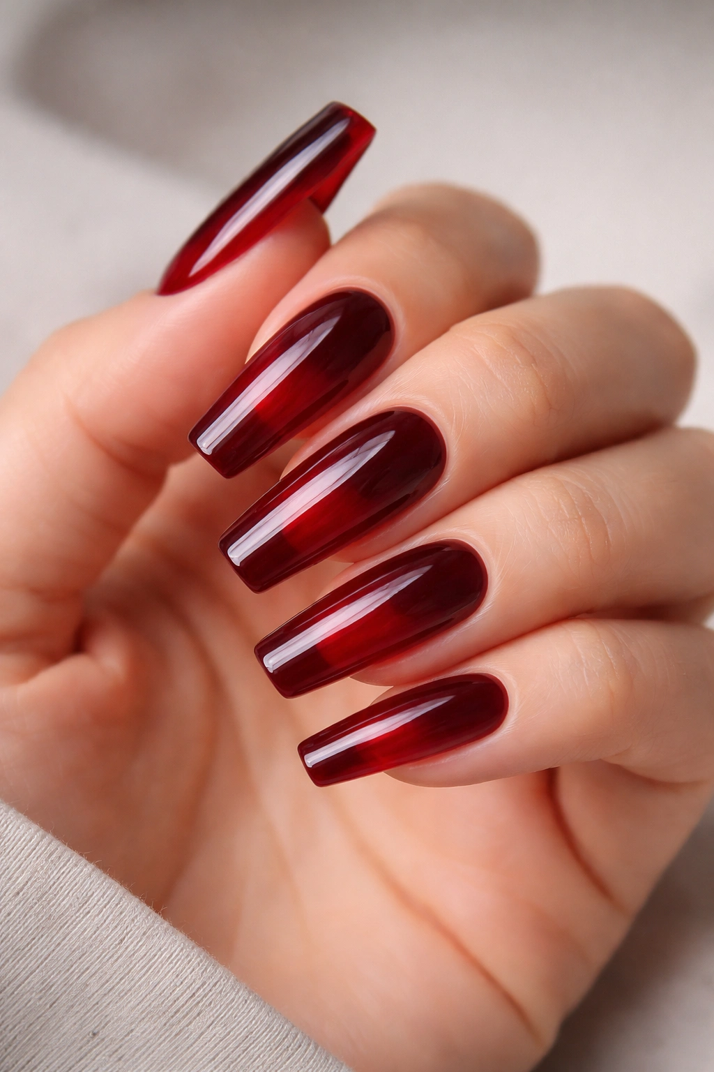 Close-up of dark red jelly layered ballerina nails with glossy depth and translucent edges.