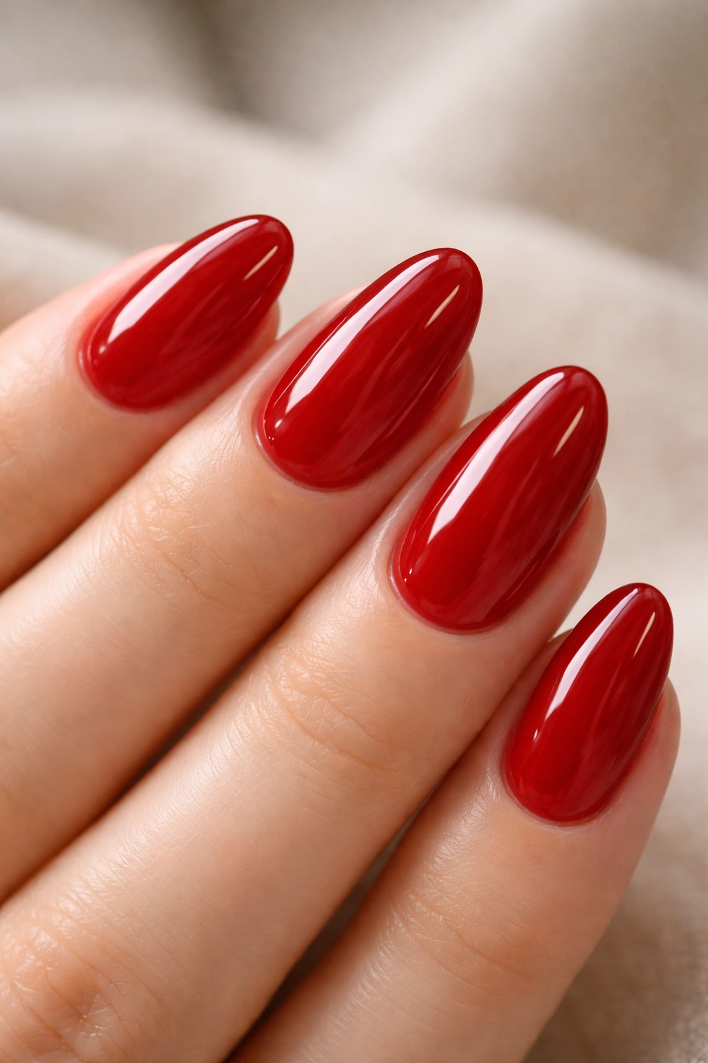 Close-up of short almond nails with translucent cherry red jelly polish