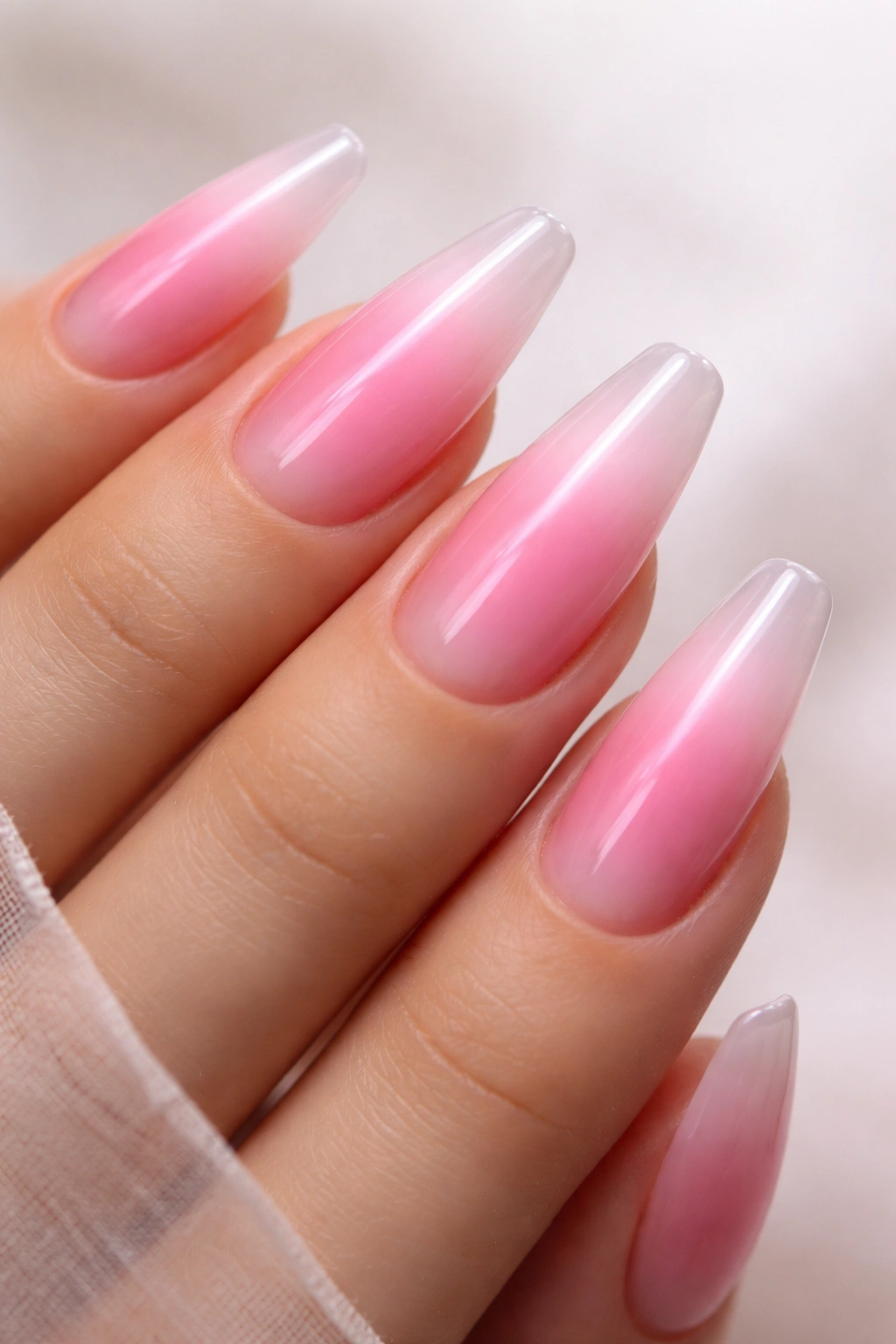 Close-up of jelly pink aura nails on a ballerina shape with a glossy center glow and sheer edges.