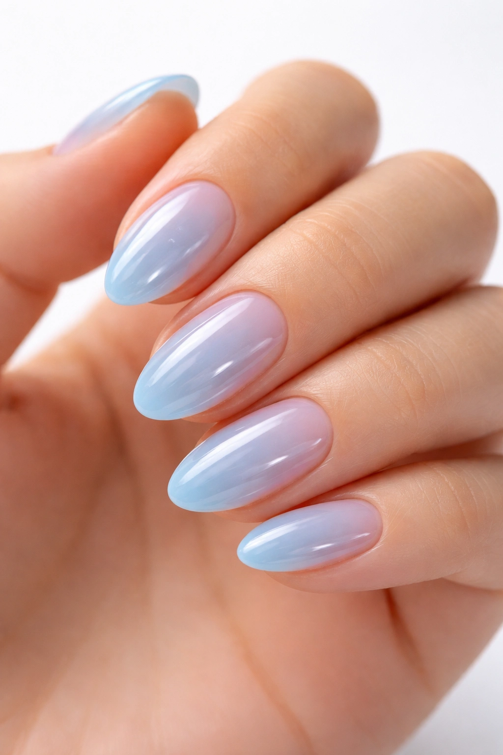 Close-up of pale ice-blue jelly nails on short almond nails with glossy translucent finish