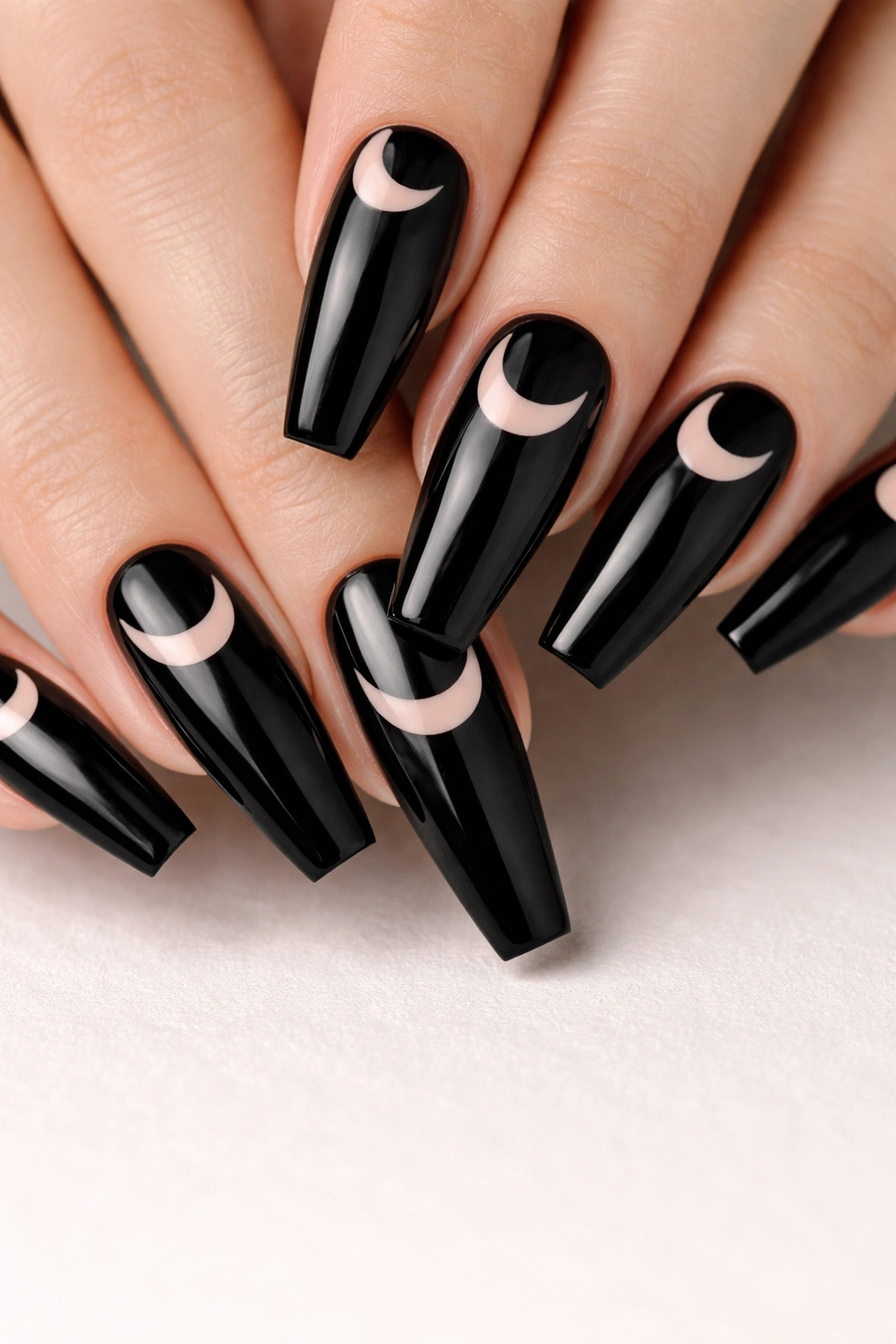 Close-up of jet-black coffin nails with negative space moon designs